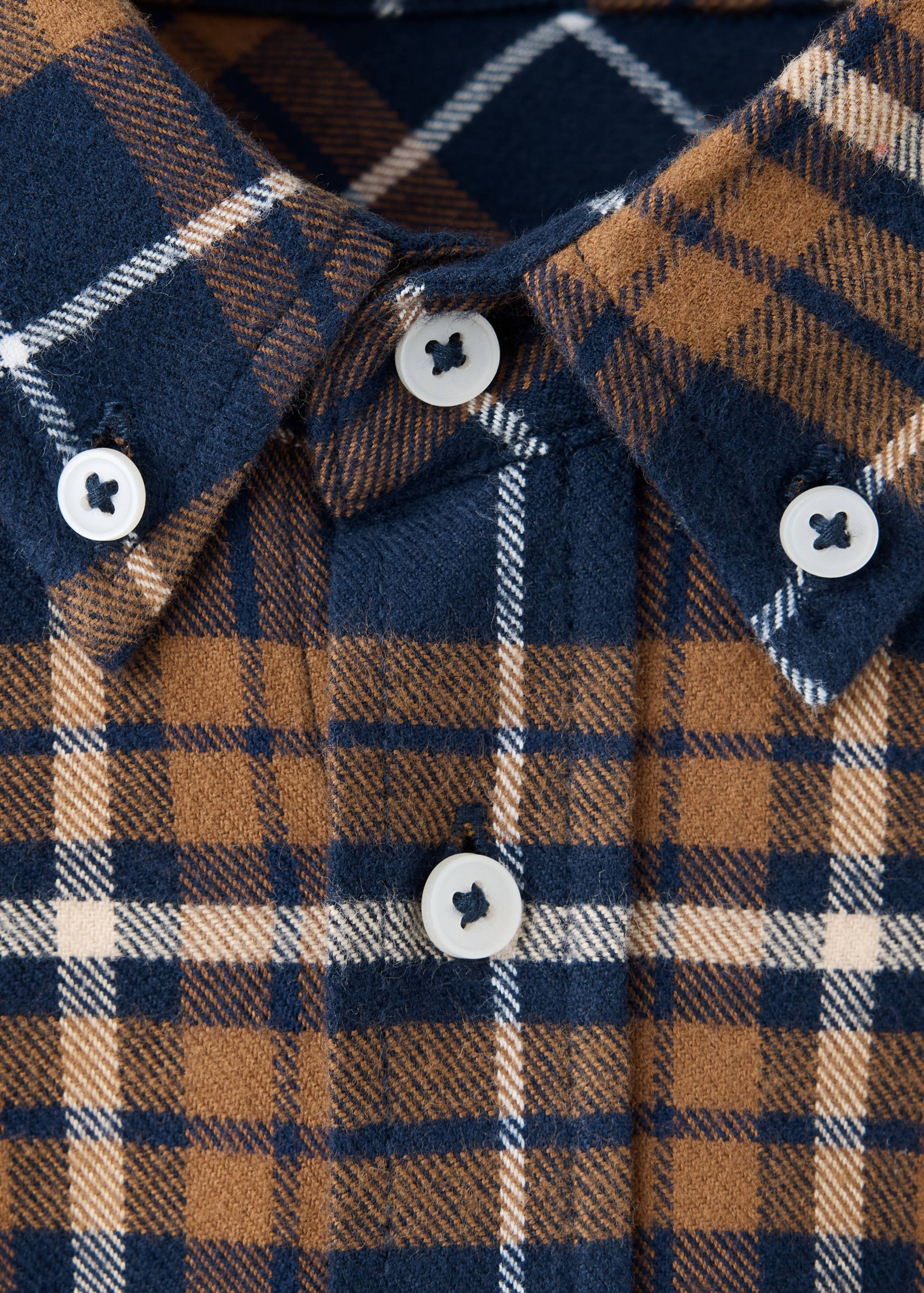 Close-up of a brown, navy blue, and white plaid teen shirt with button-down collar.