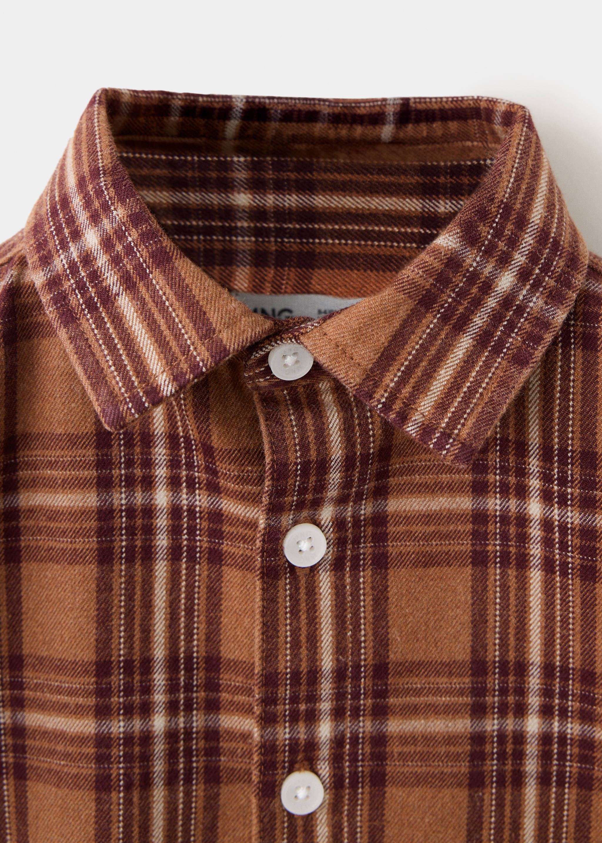 Close-up of a brown check shirt collar and button placket.