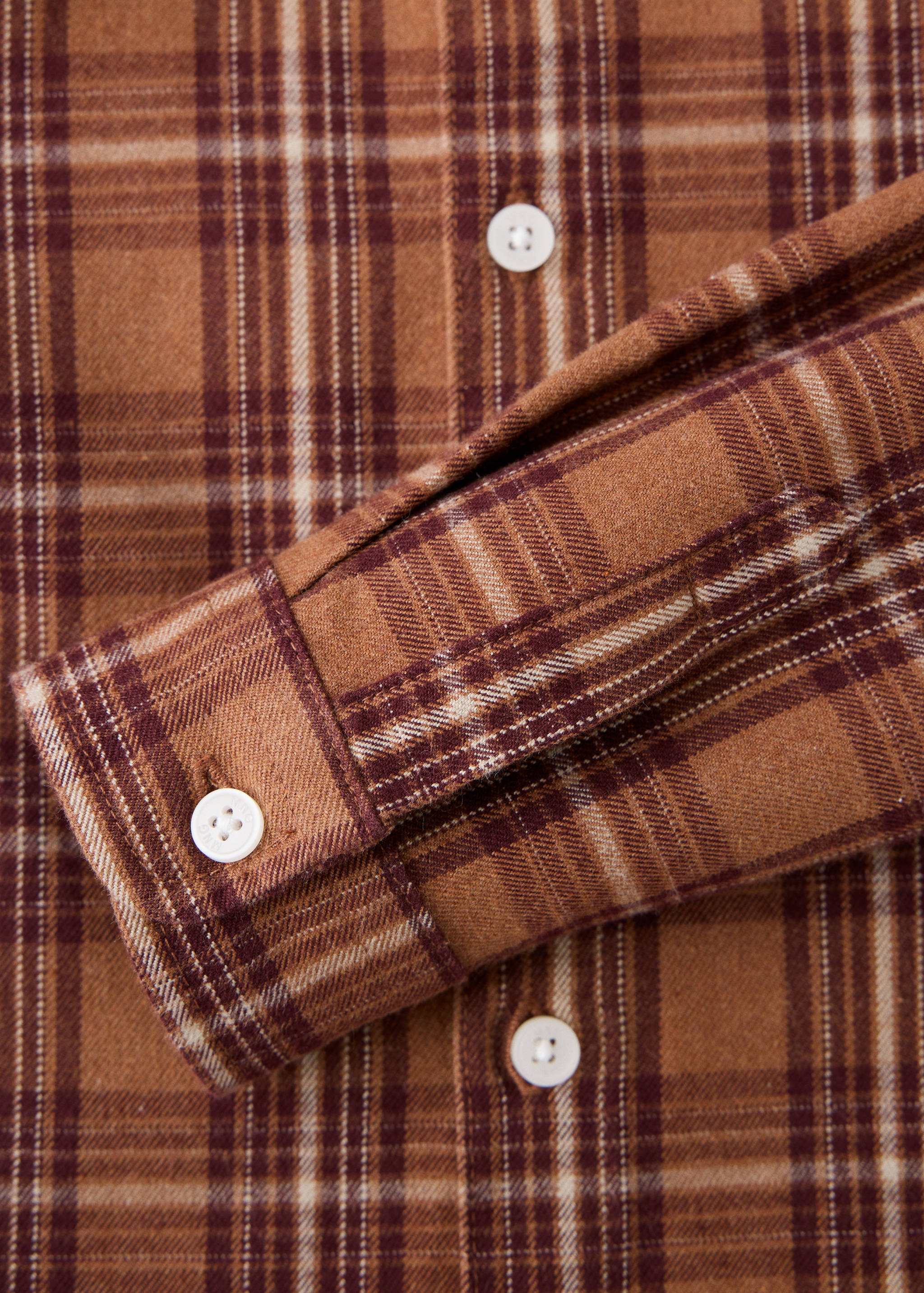 Brown plaid children's shirt fabric and buttoned cuff detail.