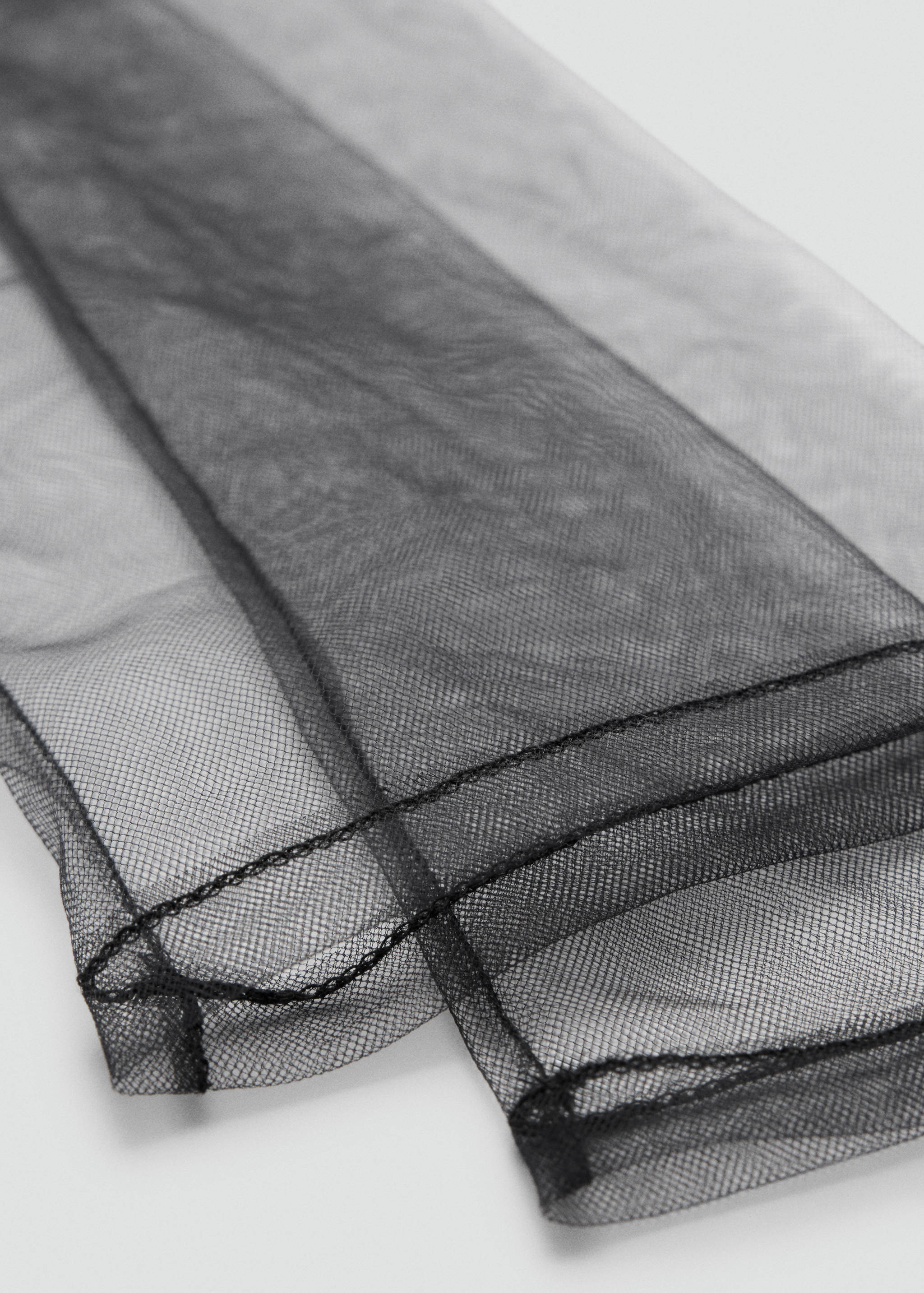 Close-up of sheer black tulle gloves showing fine seam detail.