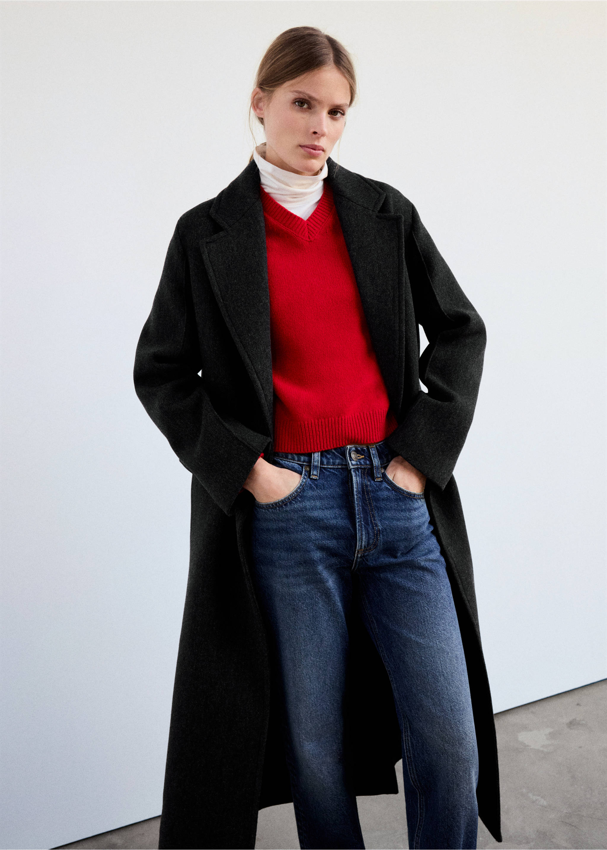 Dark grey long coat with lapels, worn over a red V-neck sweater and blue jeans., Grey. Ref: 37048640-00.