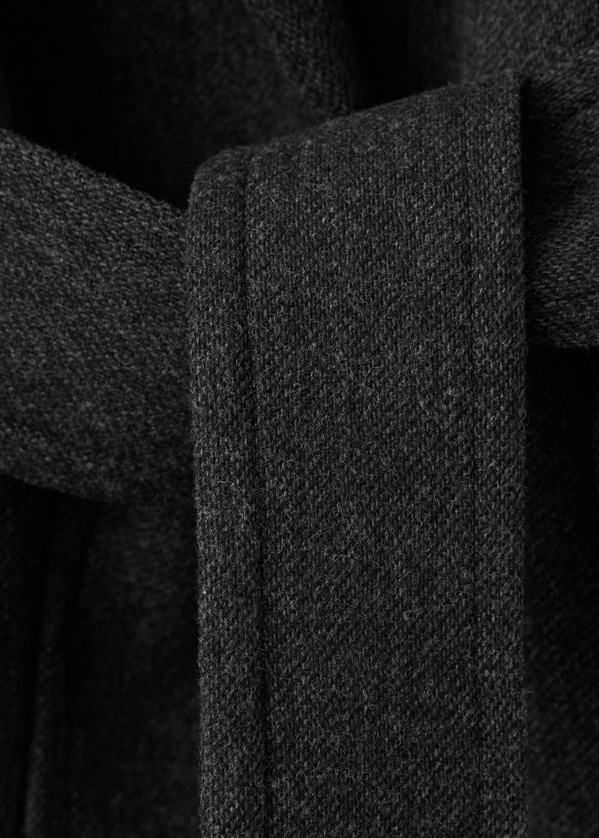 Close-up of a charcoal grey coat belt and textured fabric.