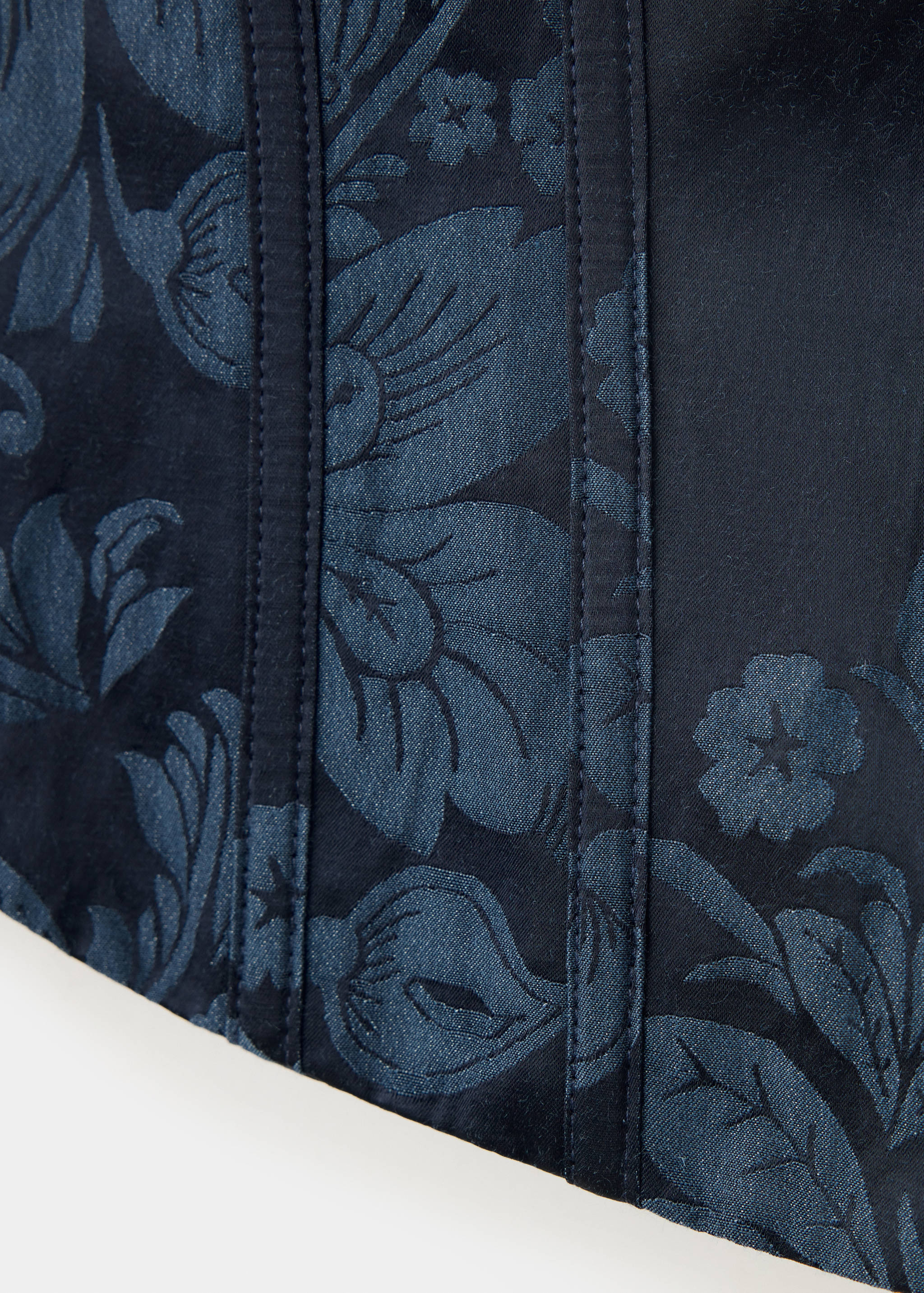 Close-up of a dark blue top with embossed floral pattern and boning.