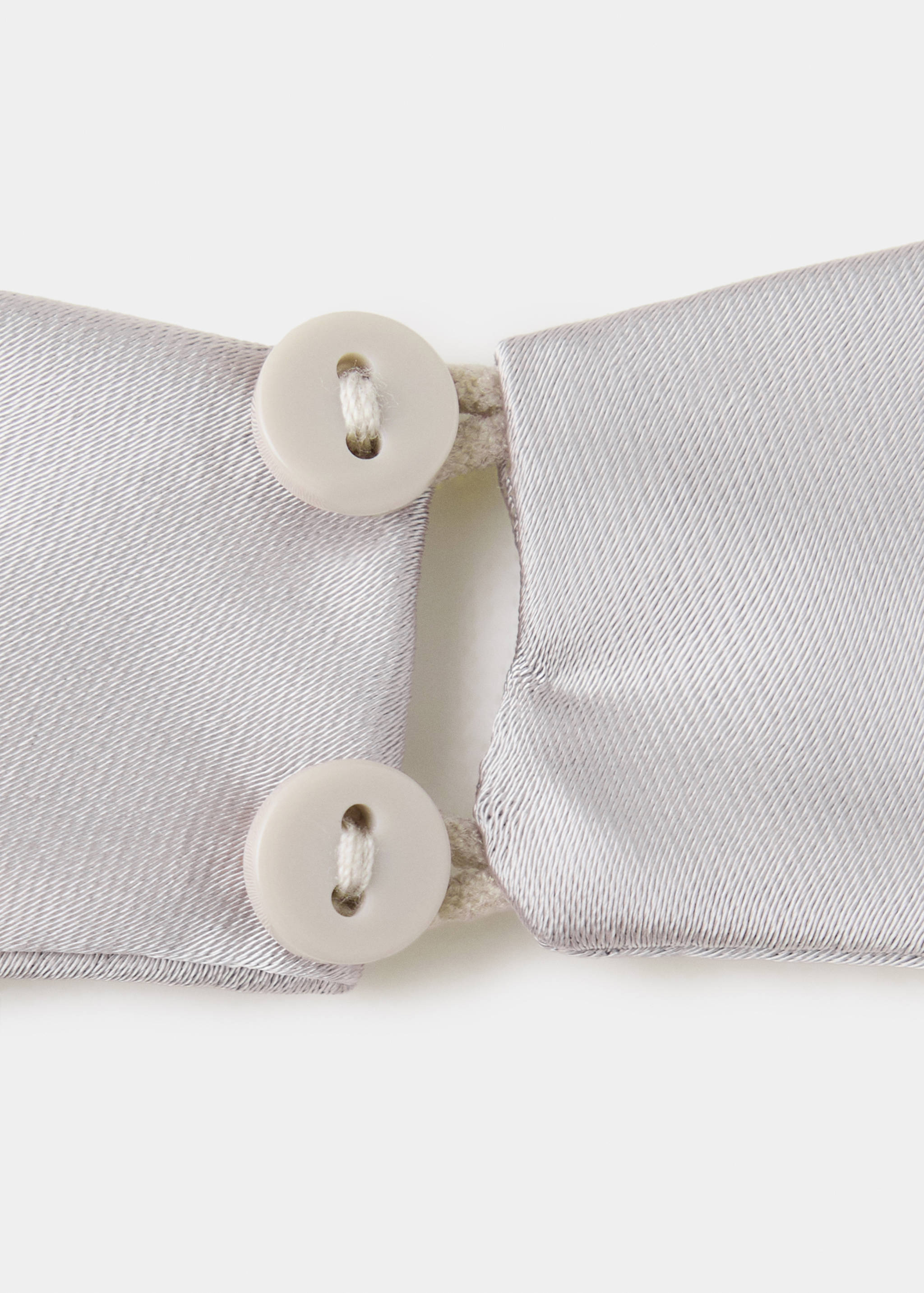 Close-up of a silver top featuring button closure detail.