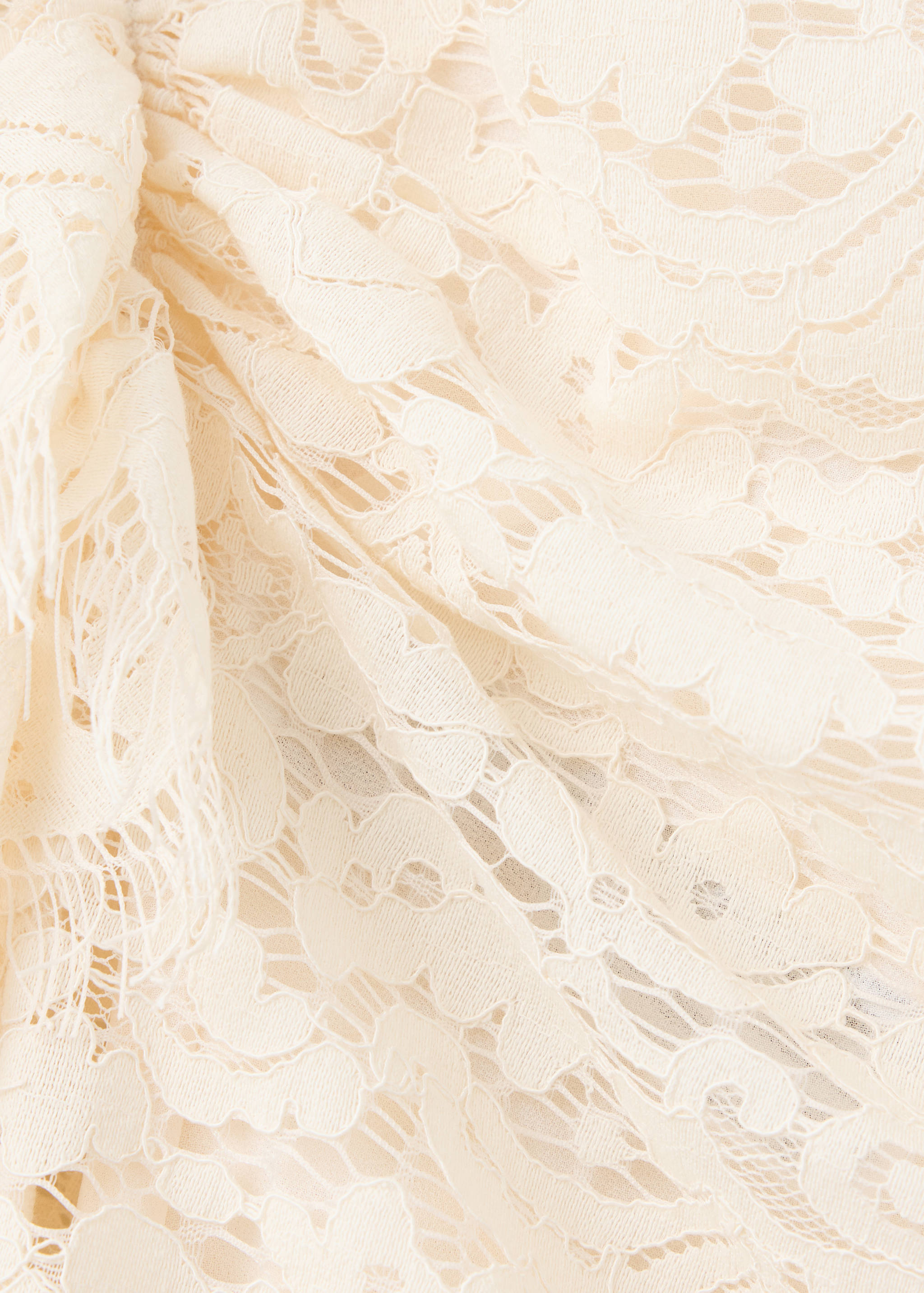 Close-up of an off-white floral lace top showing draped fabric.