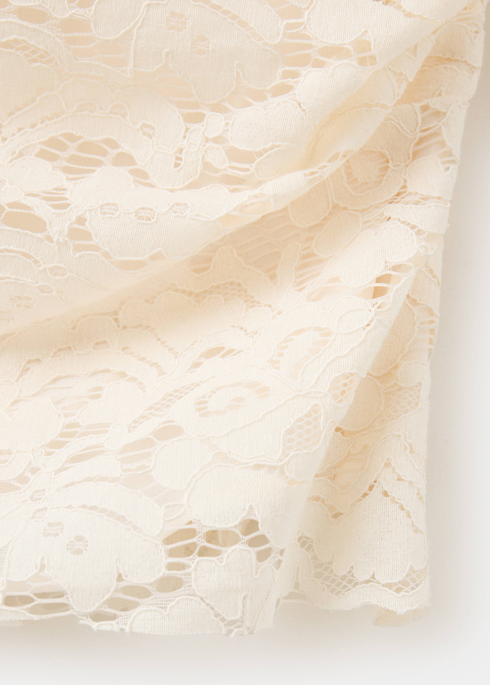 Close-up of the cream floral lace fabric on a top.