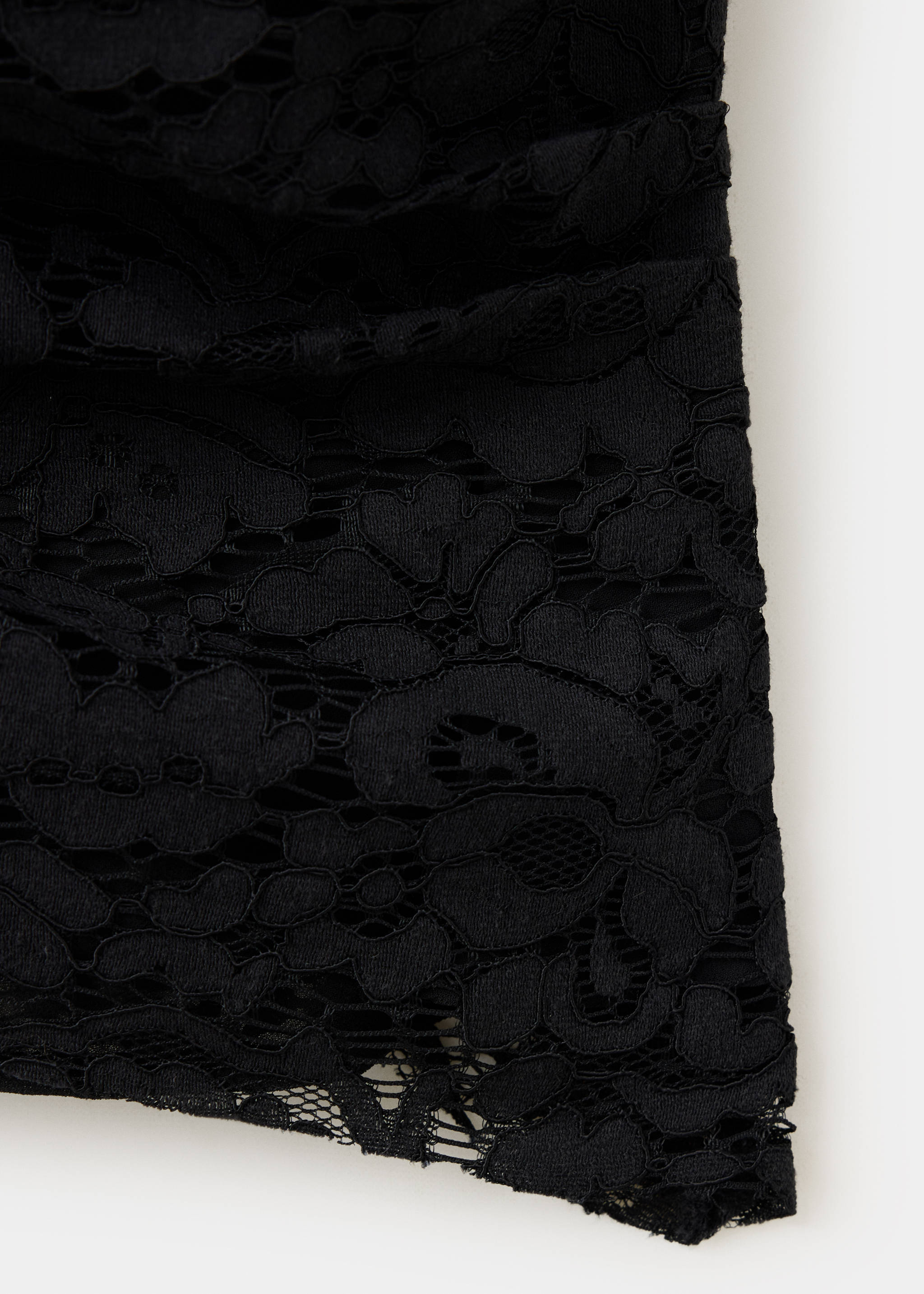 Close-up of a black top showing intricate floral lace fabric detail.