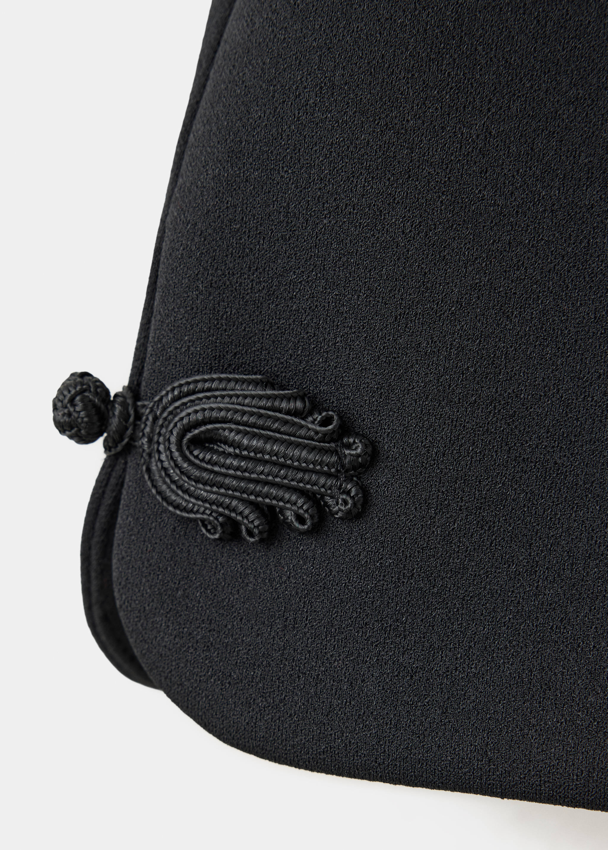 Close-up of black shorts with a decorative cord frog closure