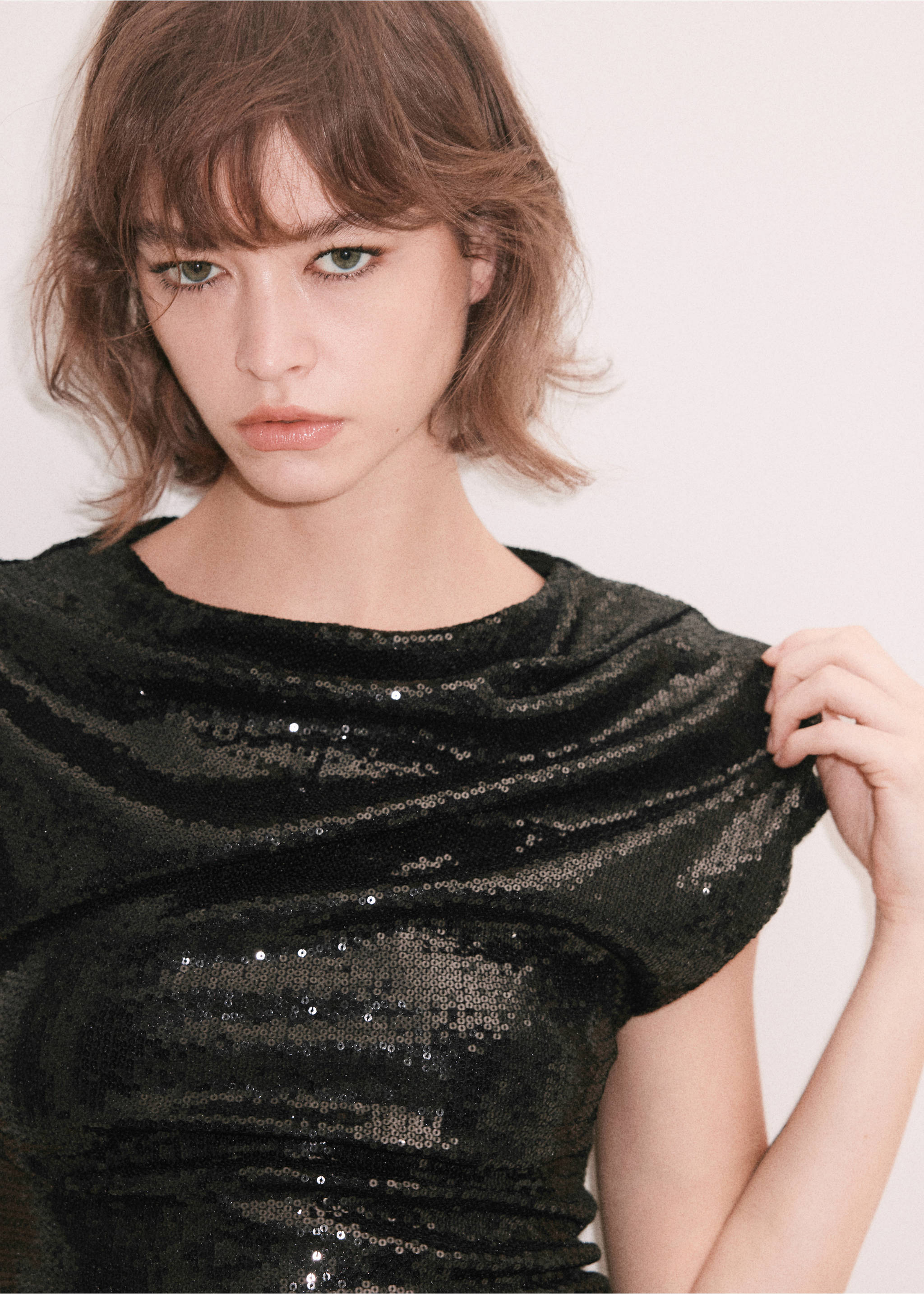Black sequinned dress with a draped neckline and cap sleeves, close-up with model, Black. Ref: 37049124-00.