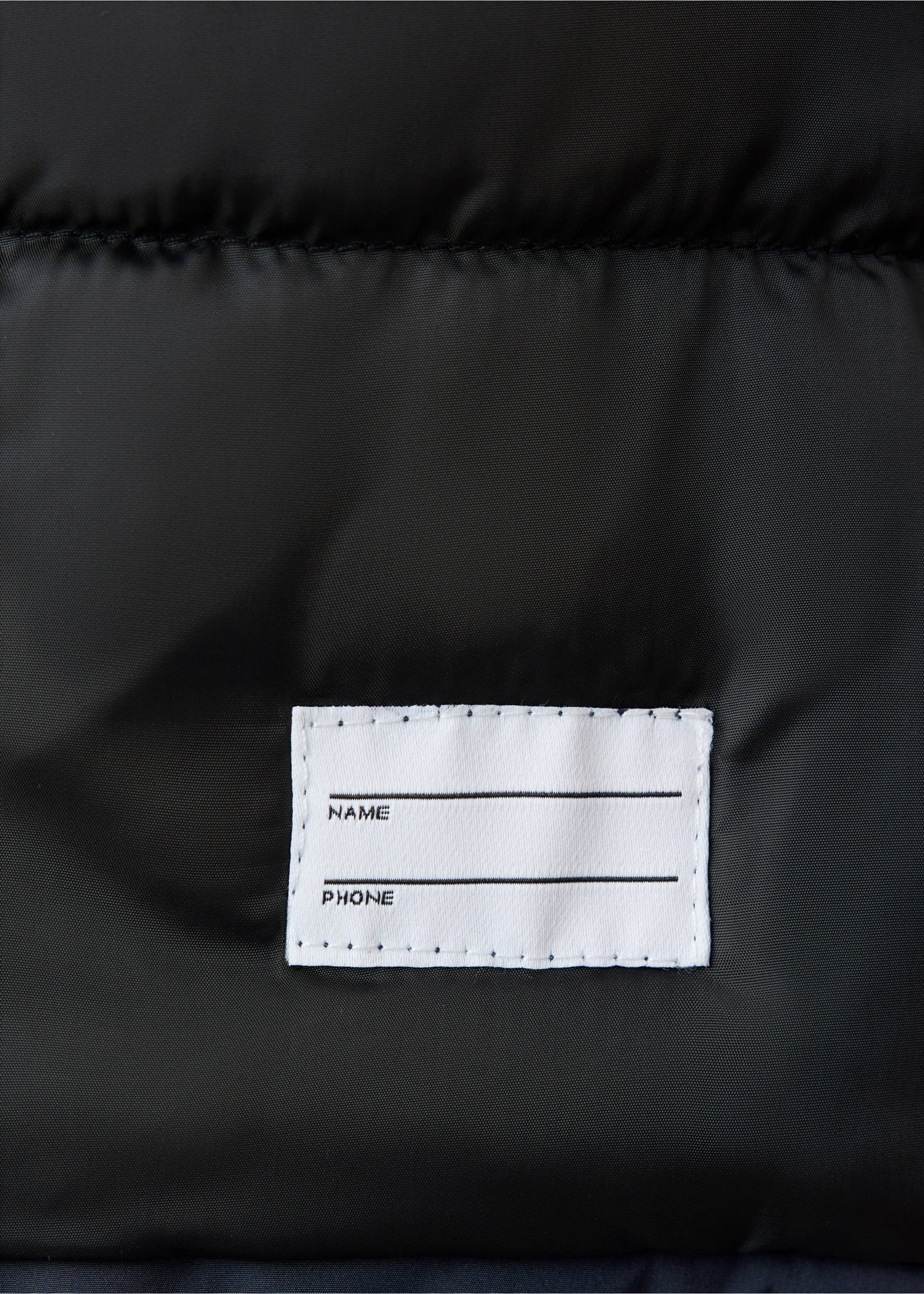 Close-up of the black anorak fabric showing an interior name and phone label., Dark Navy. Ref: 37049128-00.