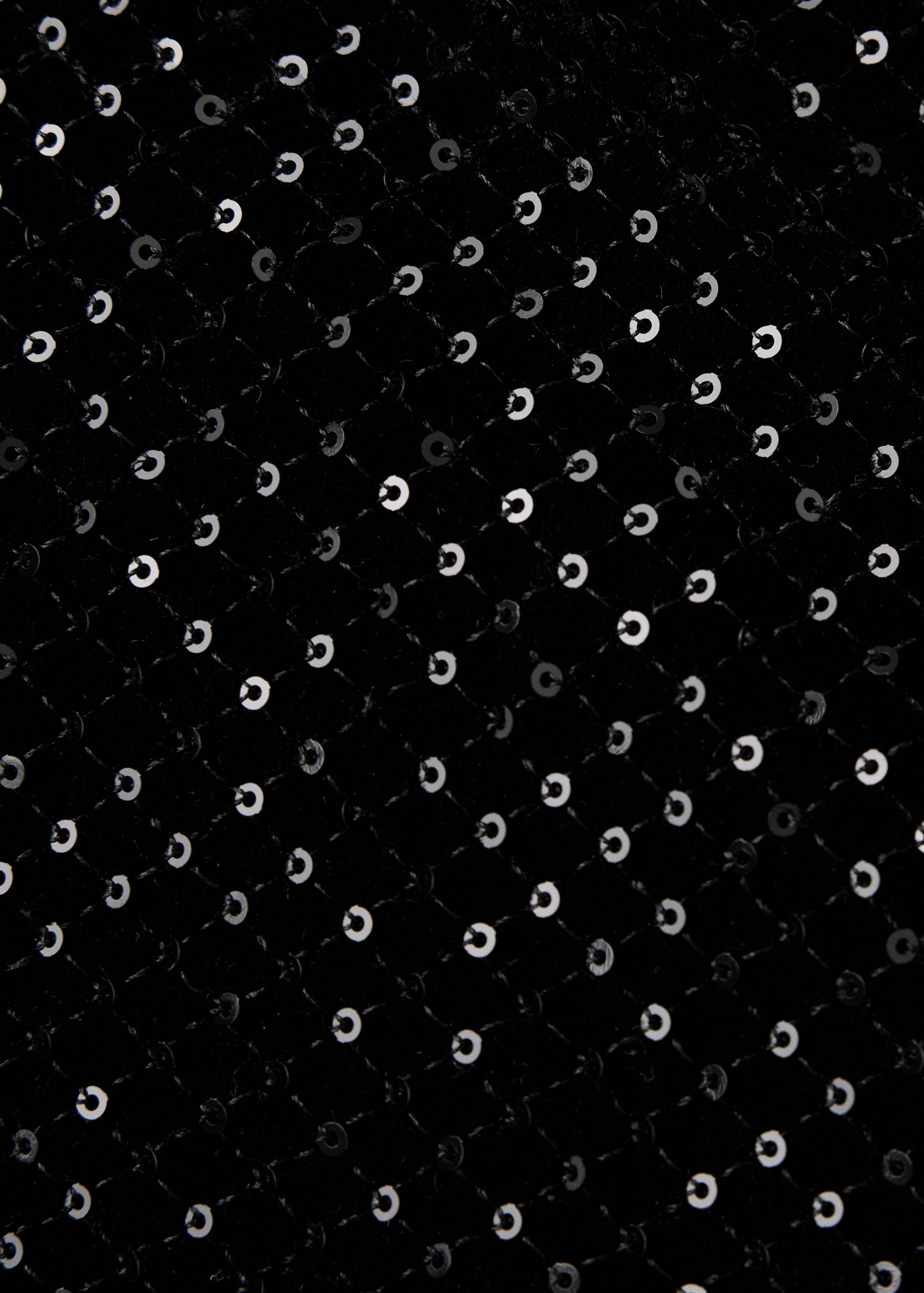 Close-up of black sequin fabric detail on shorts.