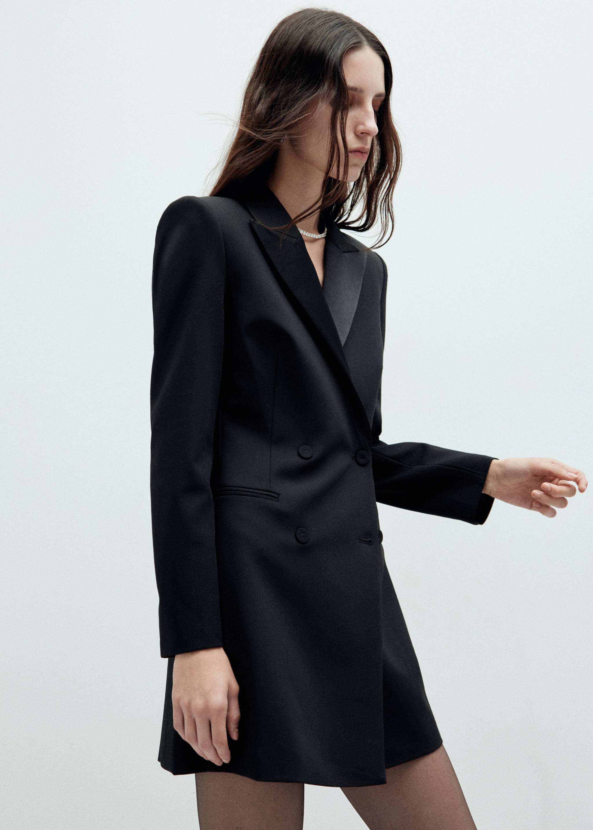 Black double-breasted blazer dress with satin lapels and structured shoulders.