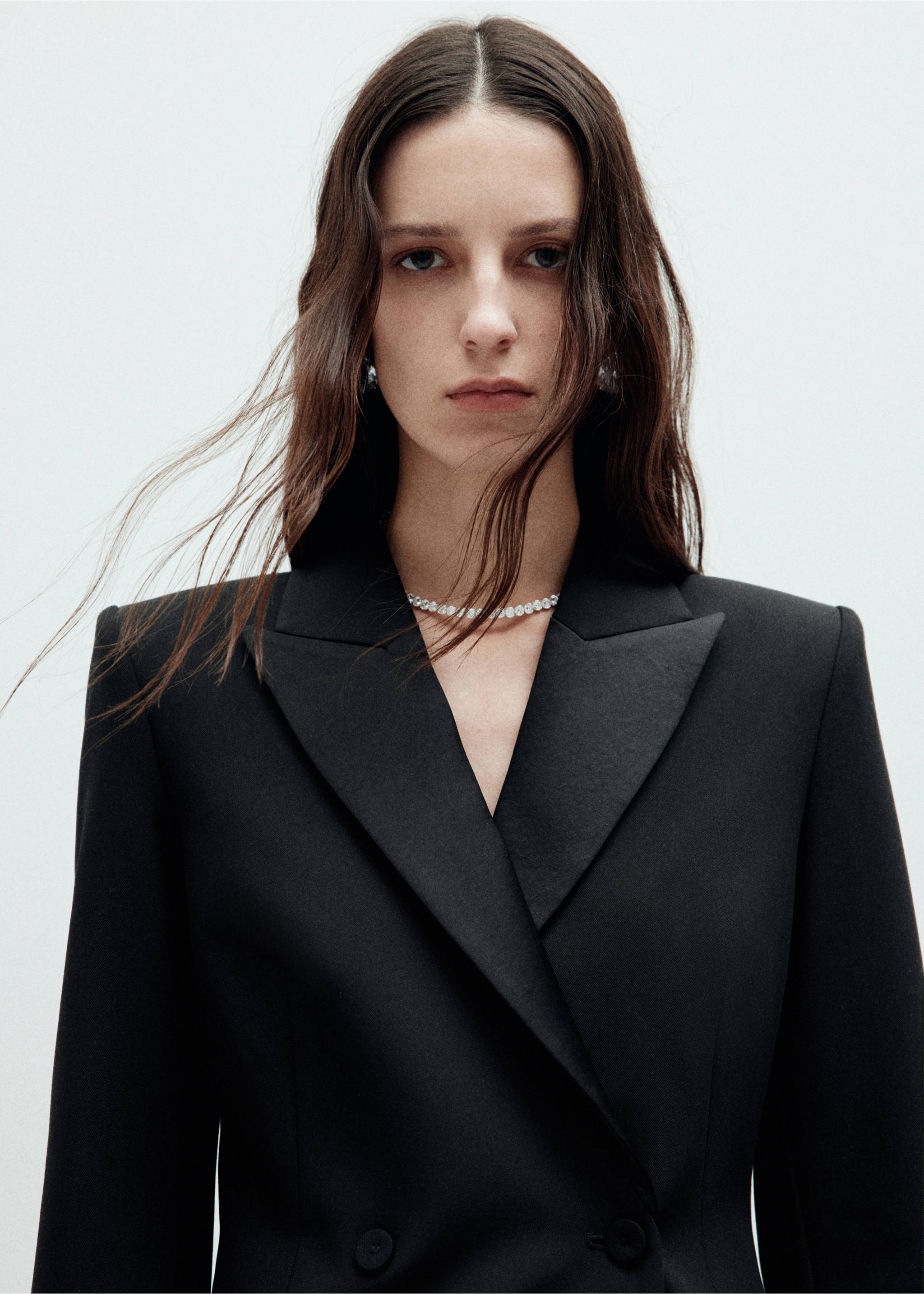 Close-up of a model wearing a black double-breasted dress with wide lapels., Black. Ref: 37049131-00.