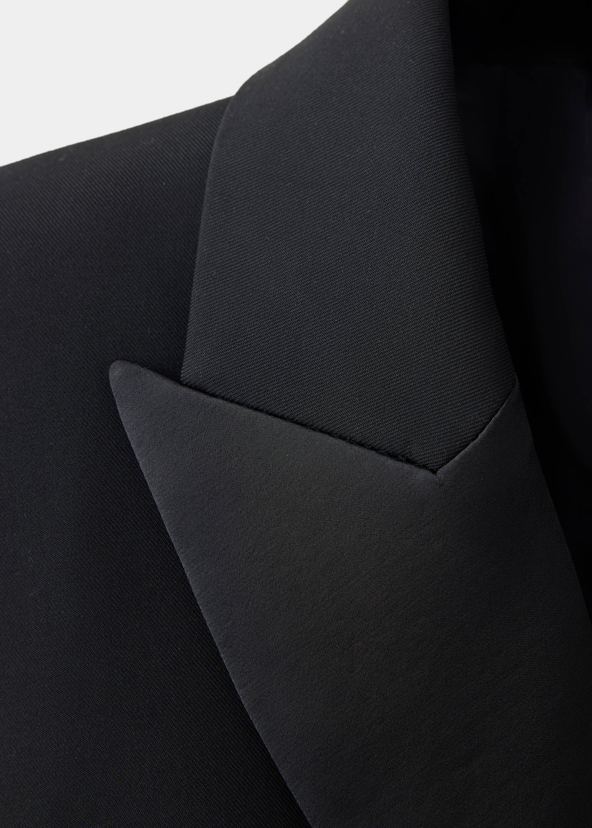 Close-up of a black dress showing a peaked satin lapel.