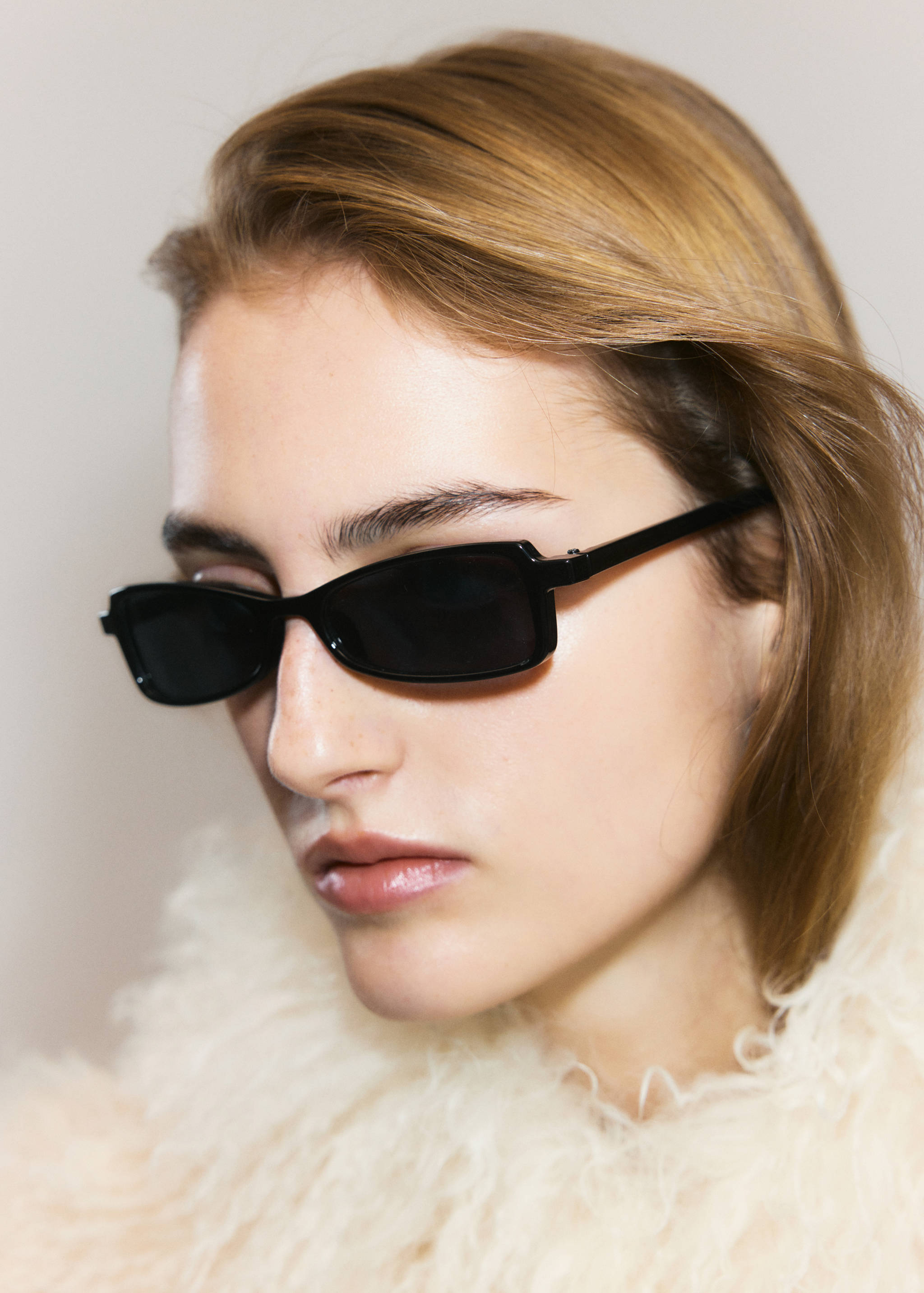 Black rectangular sunglasses with dark lenses worn by a model.