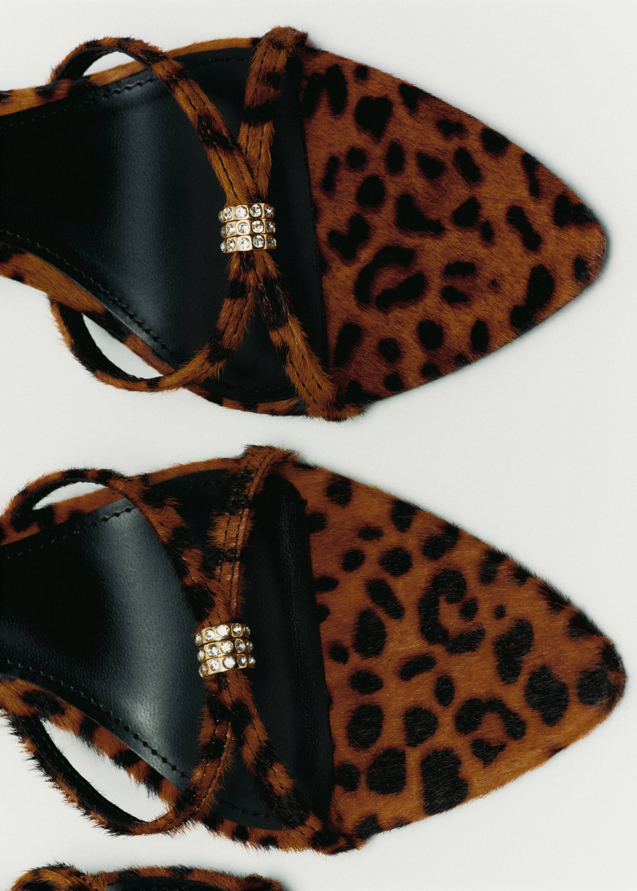 Close-up of leopard-print sandals with rhinestone-embellished straps.