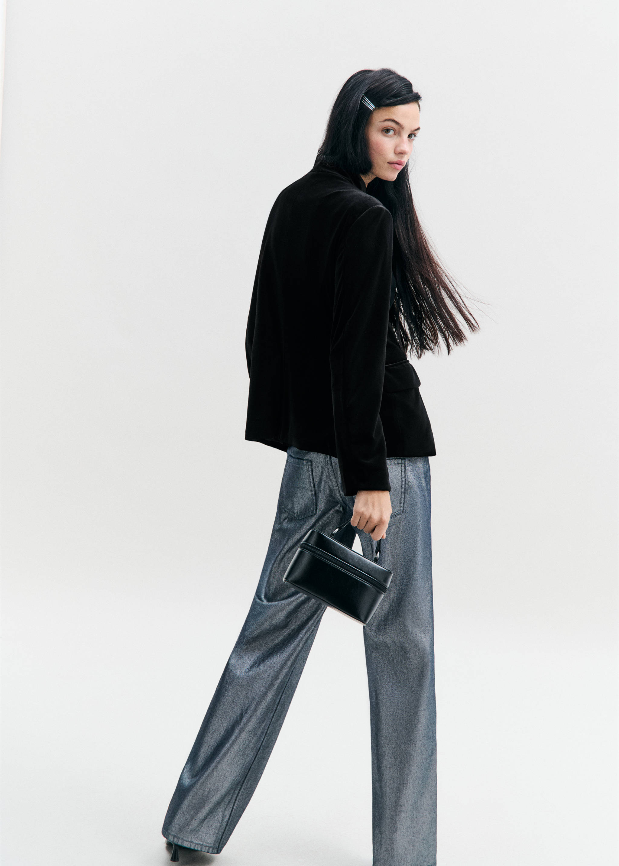 Black blazer, back view, worn with metallic grey trousers.