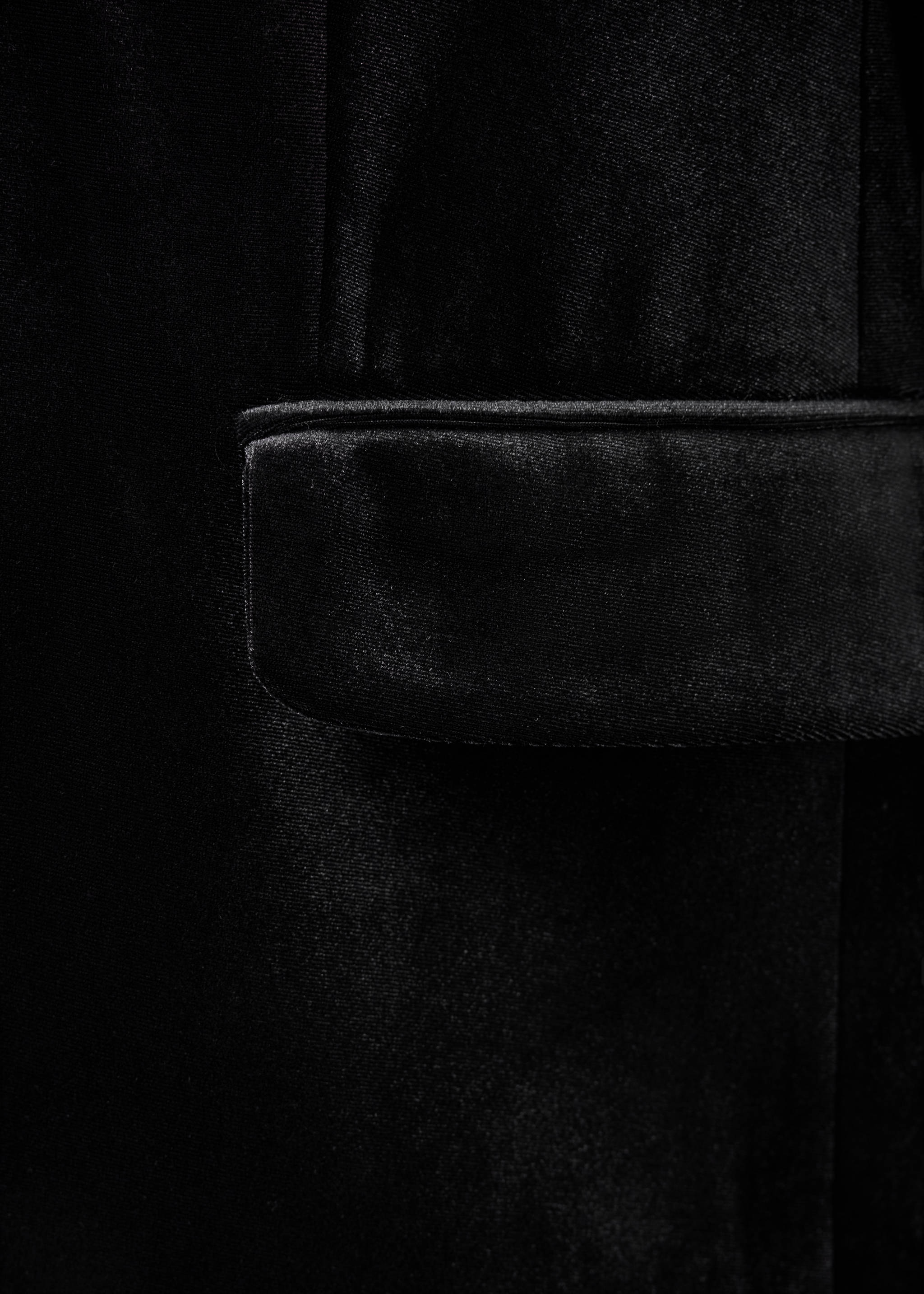 Close-up of a black velvet blazer showing a pocket detail.