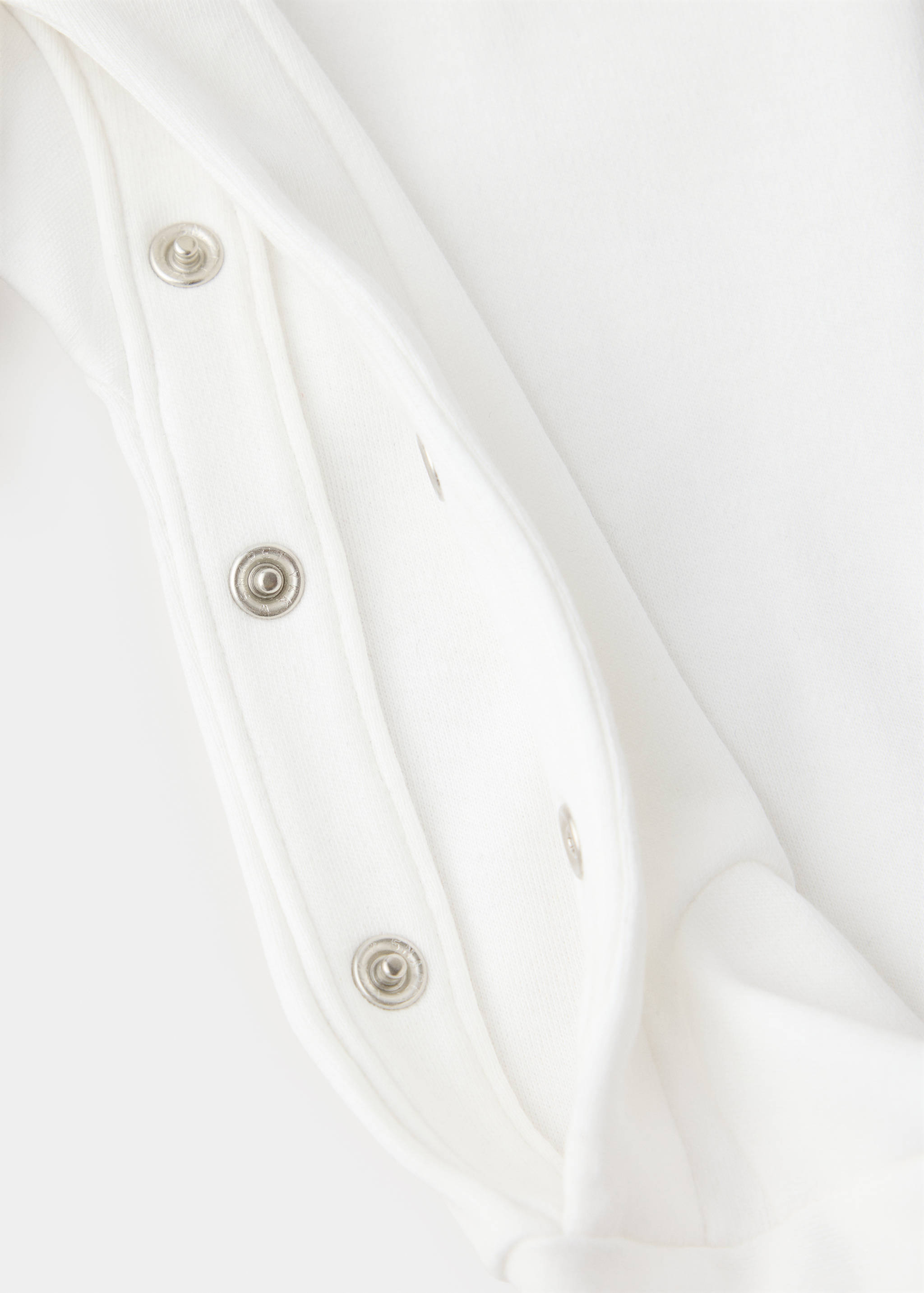 White pyjama fabric and press-stud fastening detail.