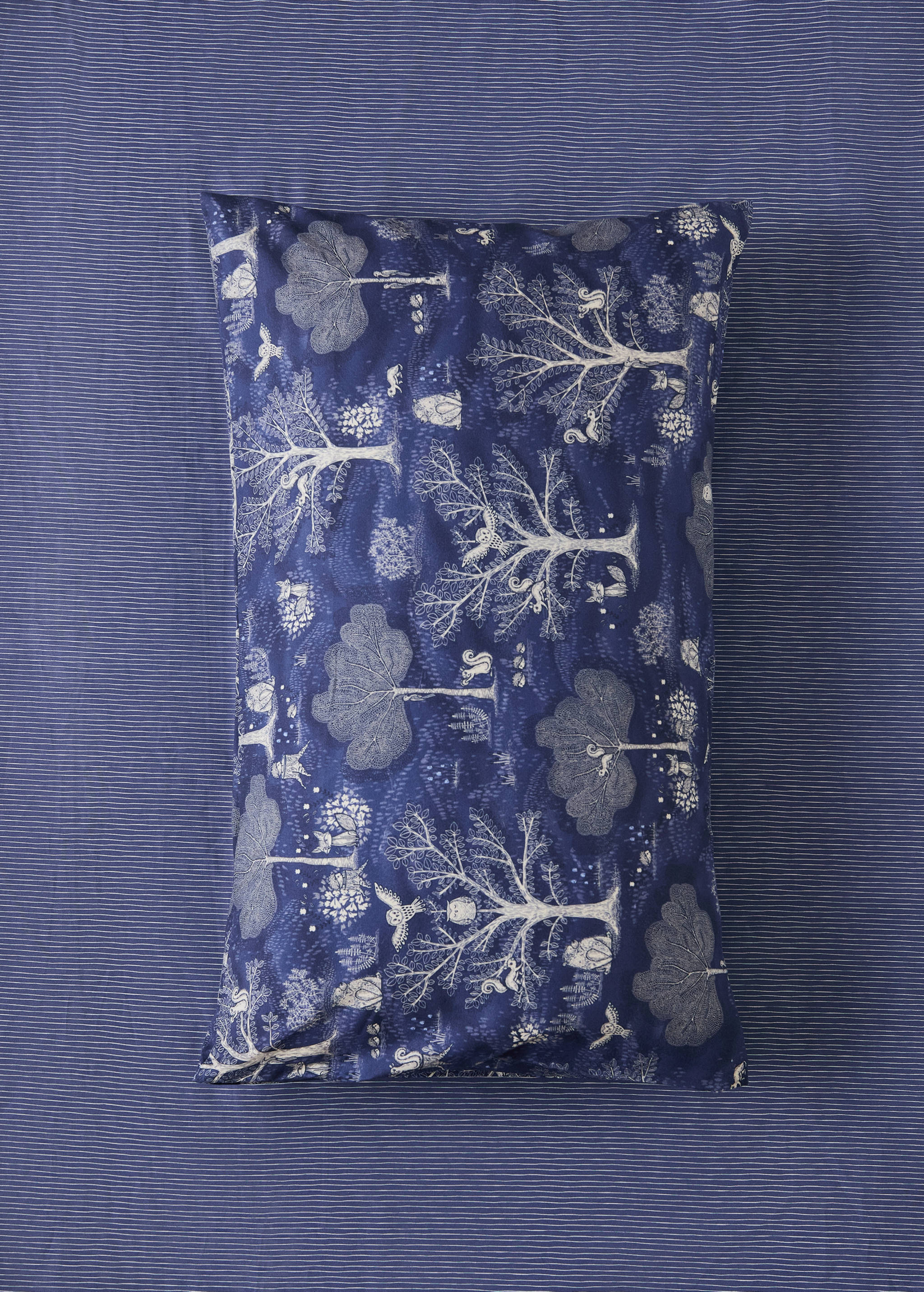 Blue woodland-print cot pillowcase with an intricate animal and tree pattern.