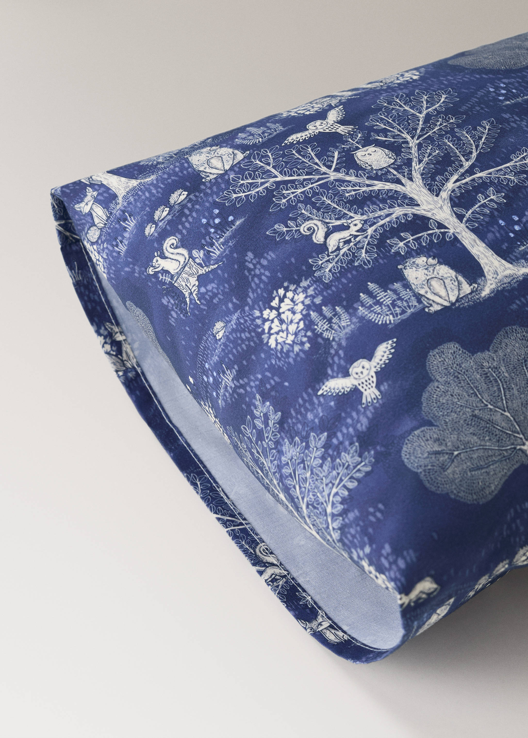 Blue cot pillowcase with white woodland animal print.