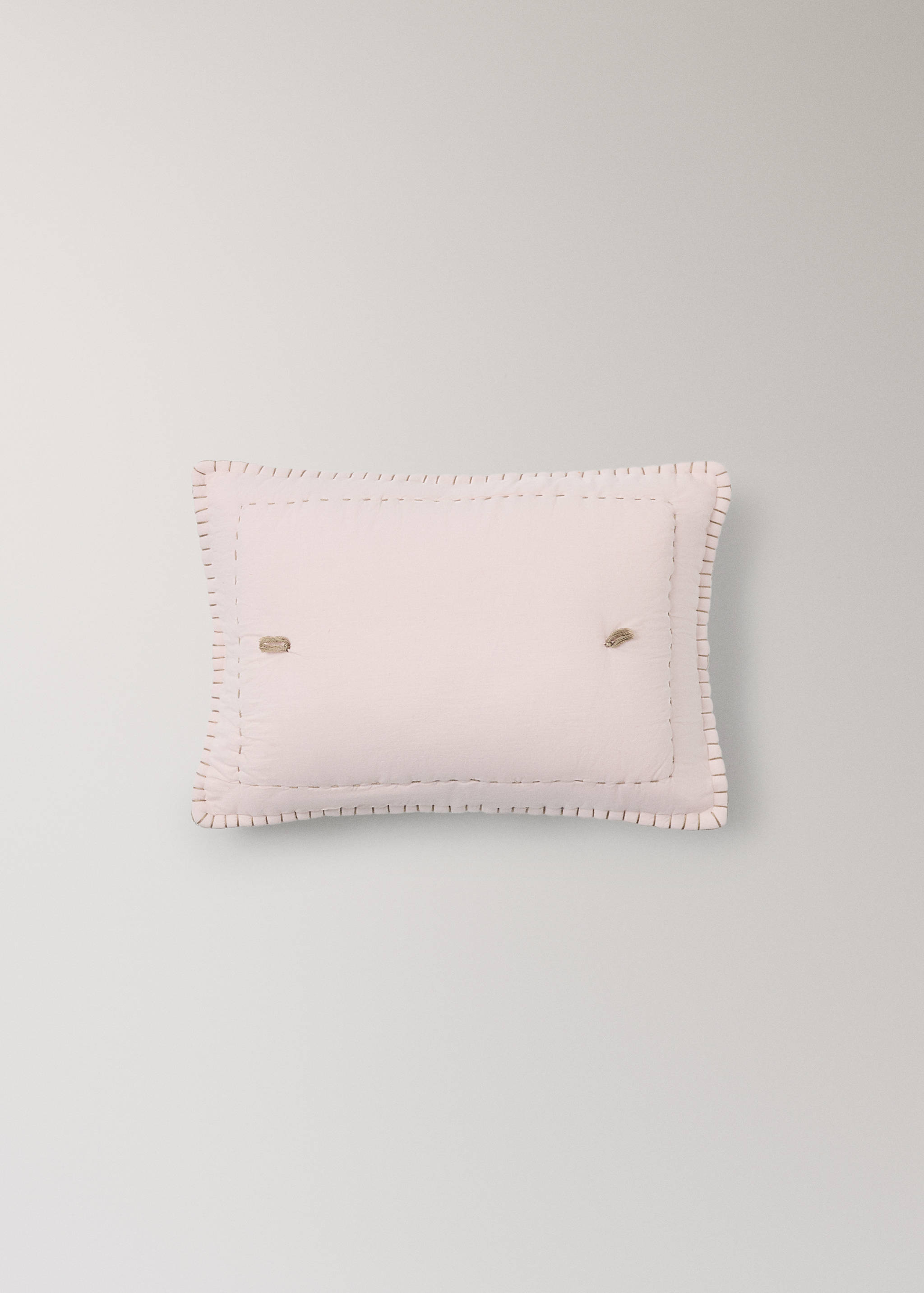 Light pink bed cushion cover with decorative stitching.