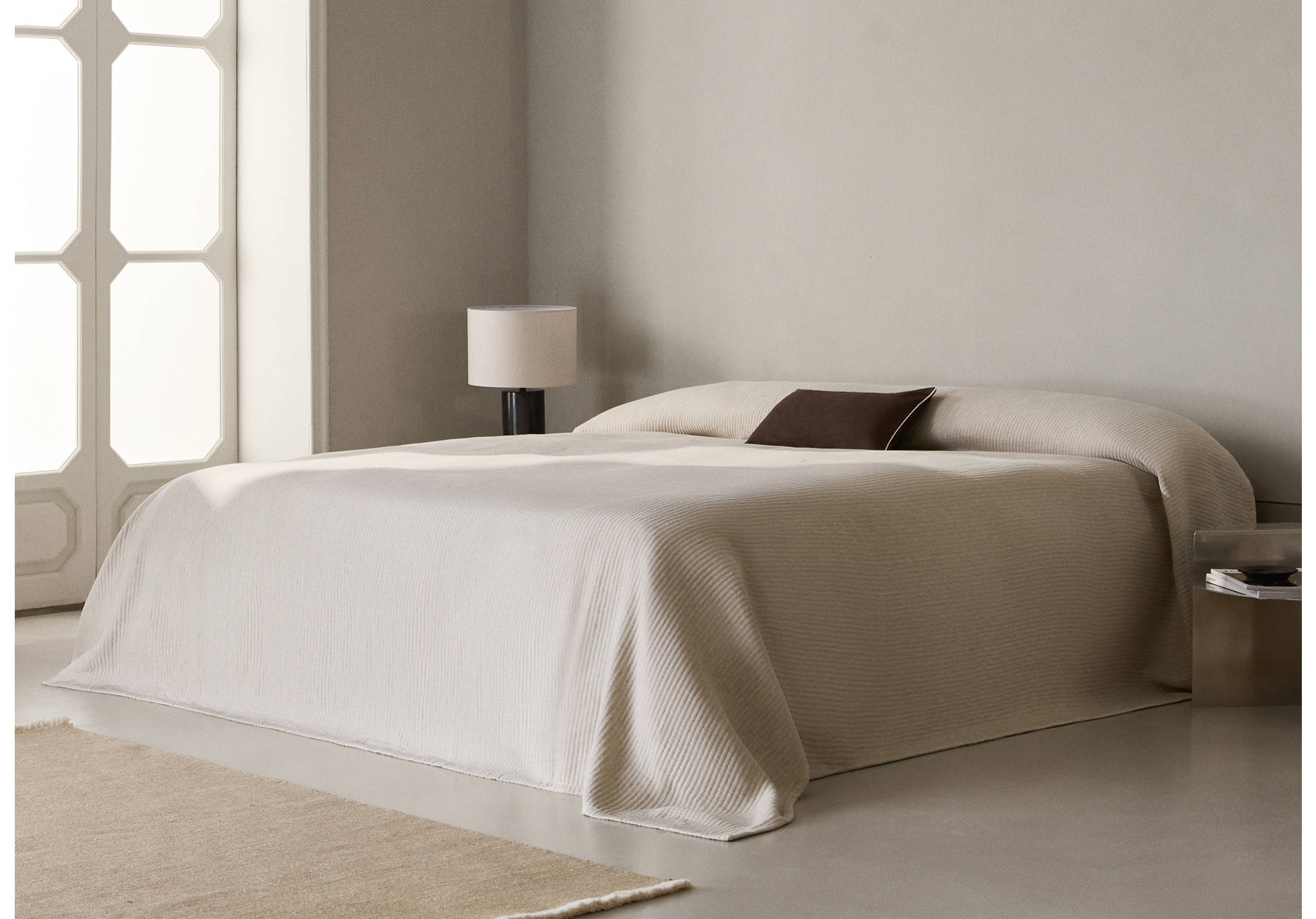 Textured ribbed beige bedspread styled on a made bed.