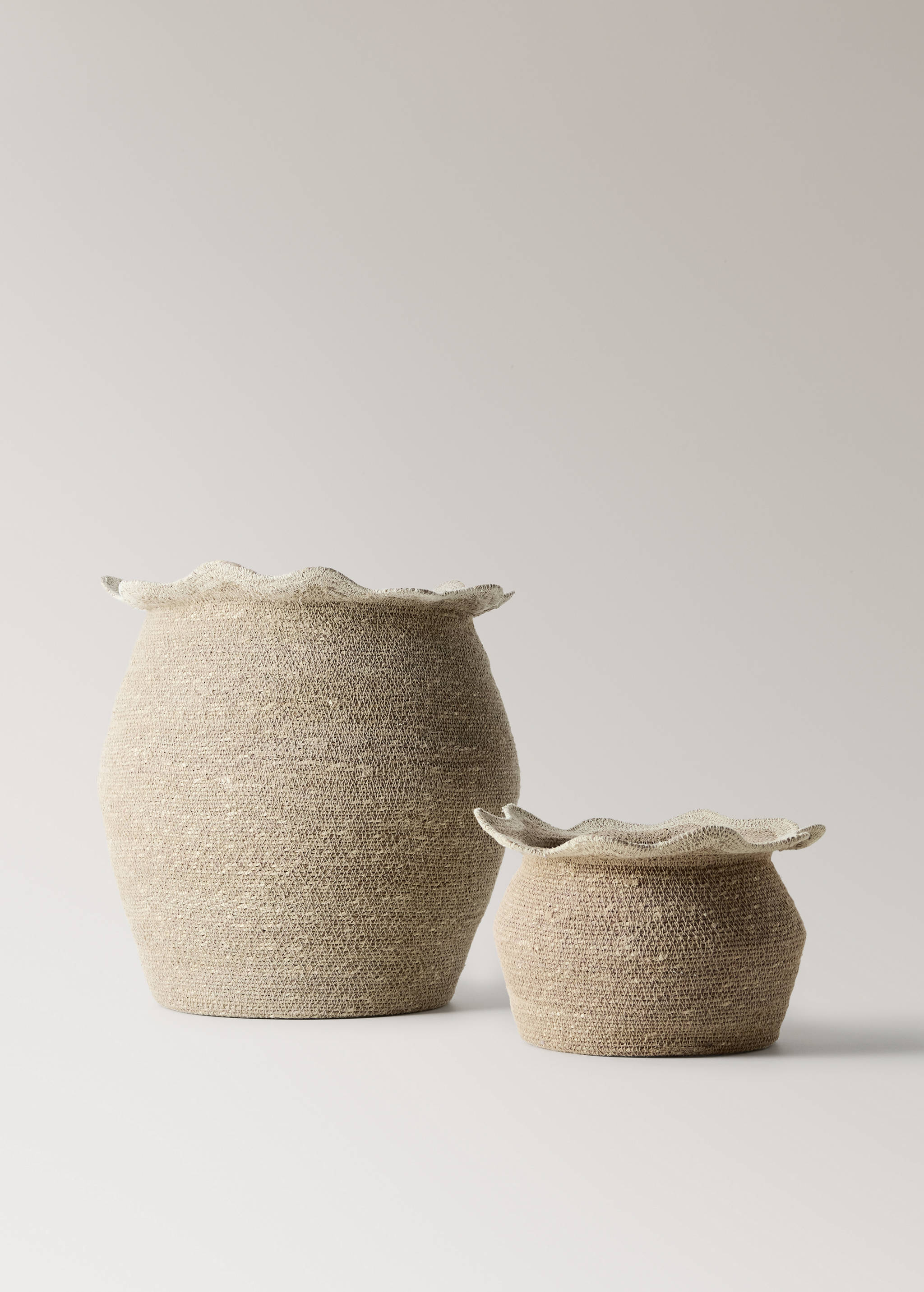 Two natural beige woven baskets with structured rounded bodies and flared ruffled rims.
