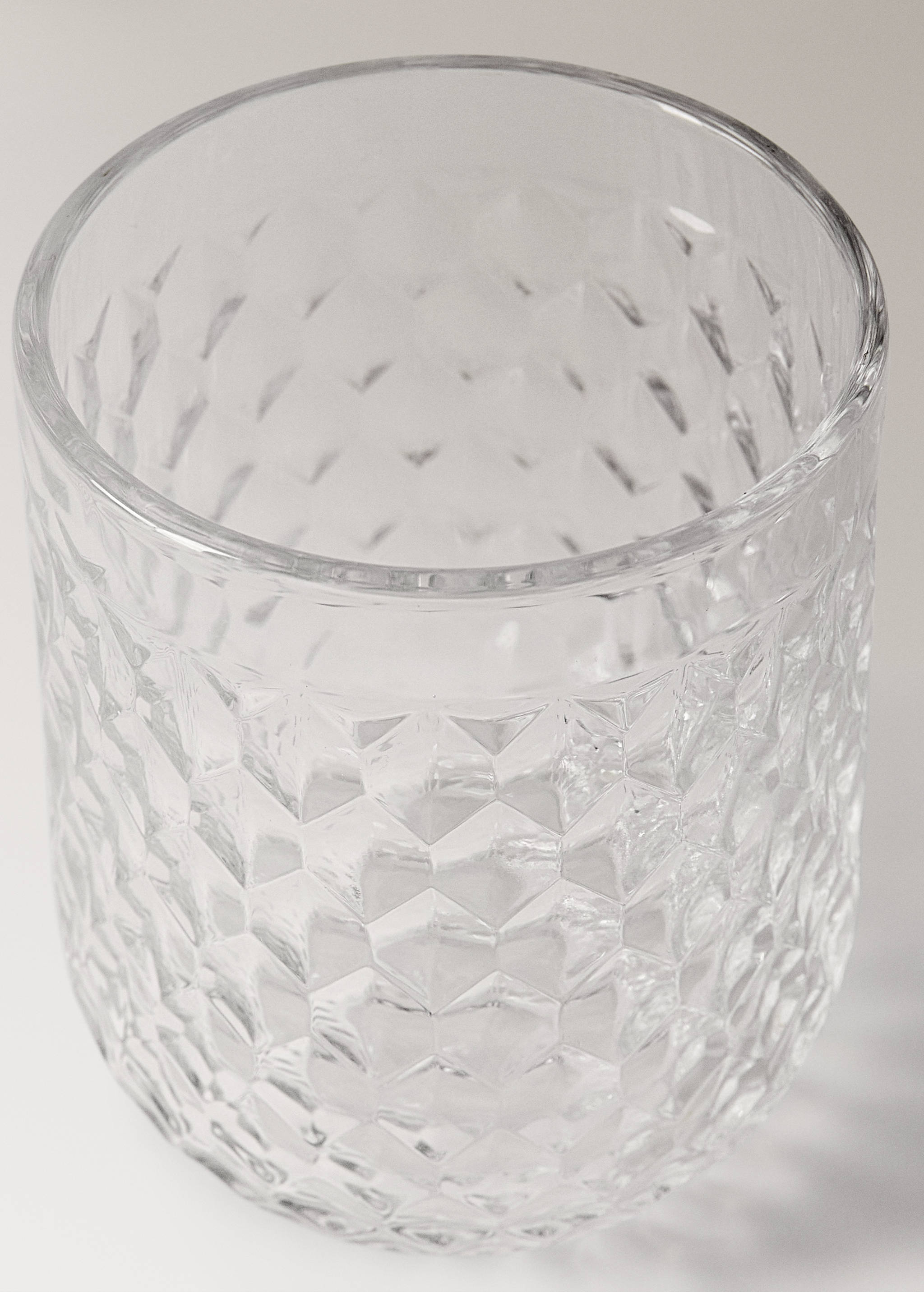 Clear glass tumbler with a faceted textured diamond pattern.