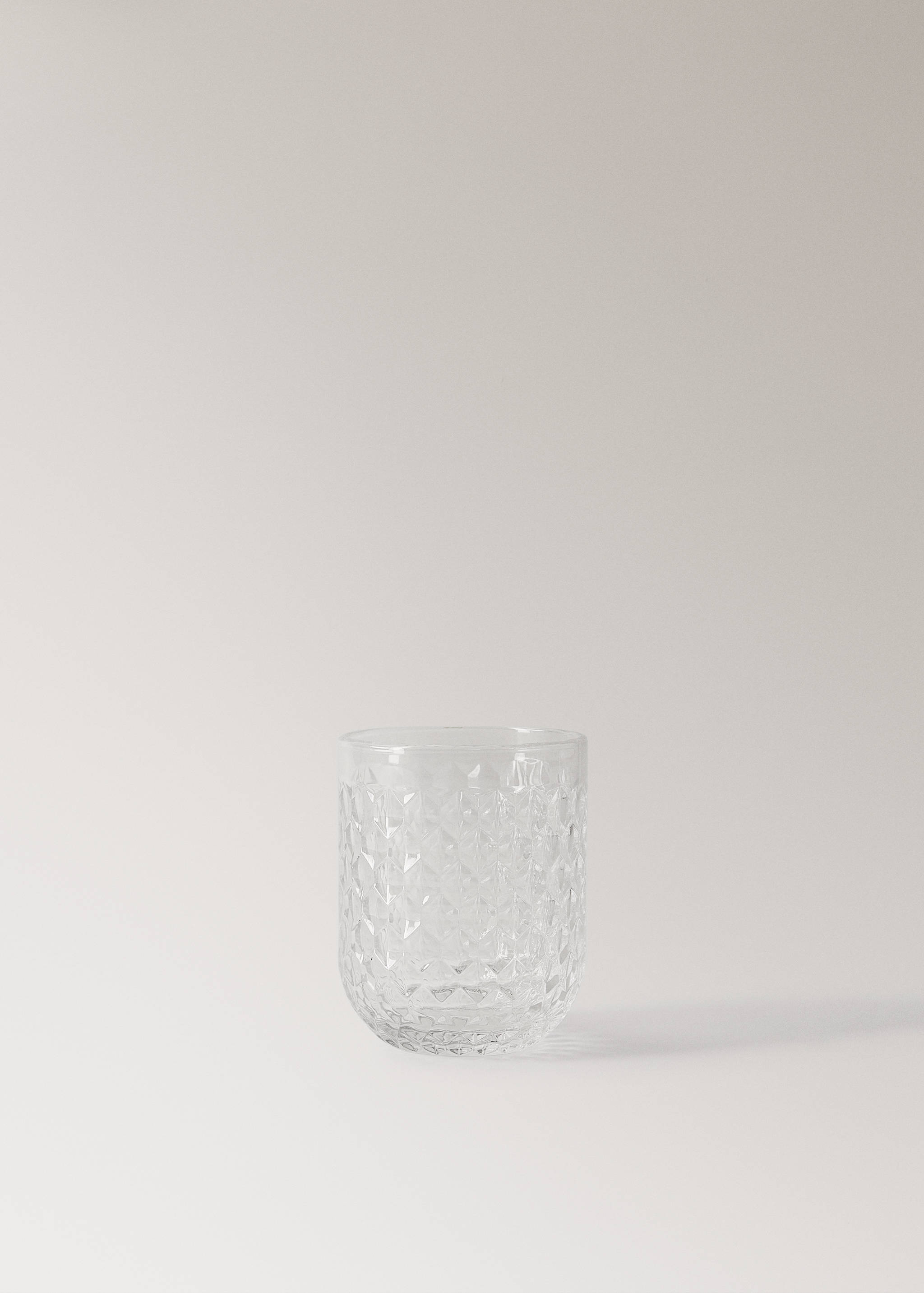 Clear glass tumbler with a geometric textured pattern.