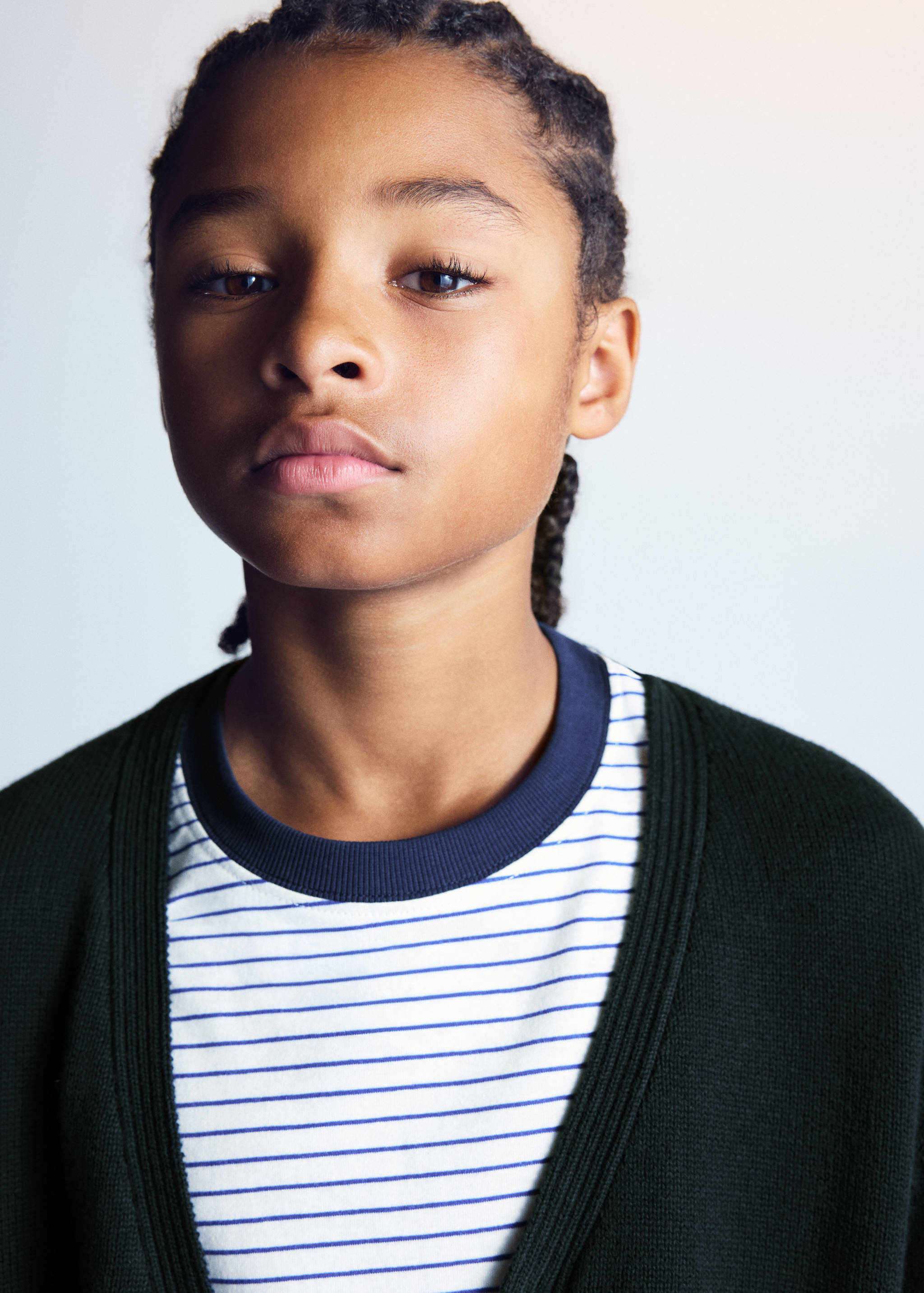 Dark green cardigan with a ribbed V-neck, worn over a striped t-shirt.