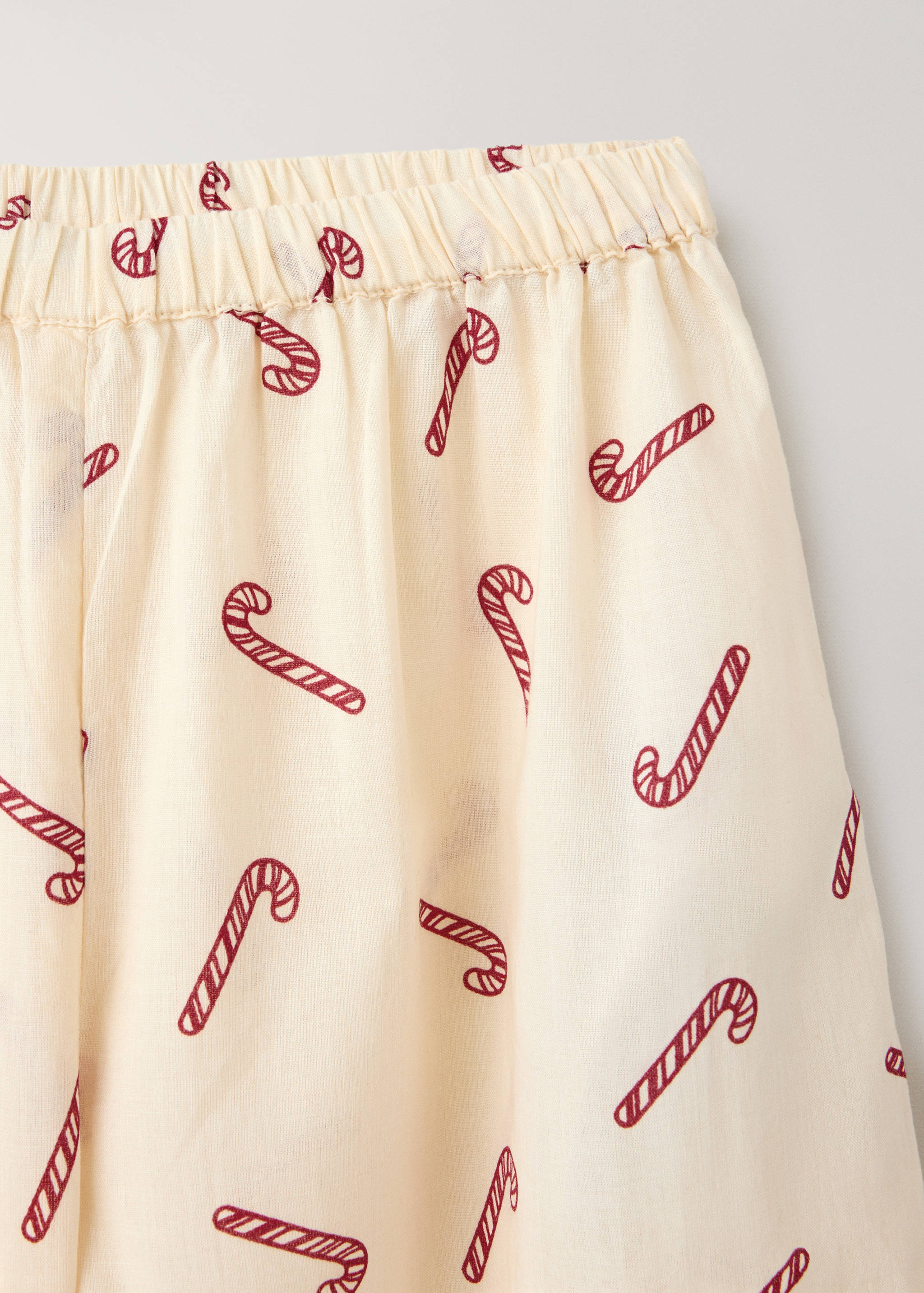 Close-up of cream pyjama trousers with a red candy cane print.