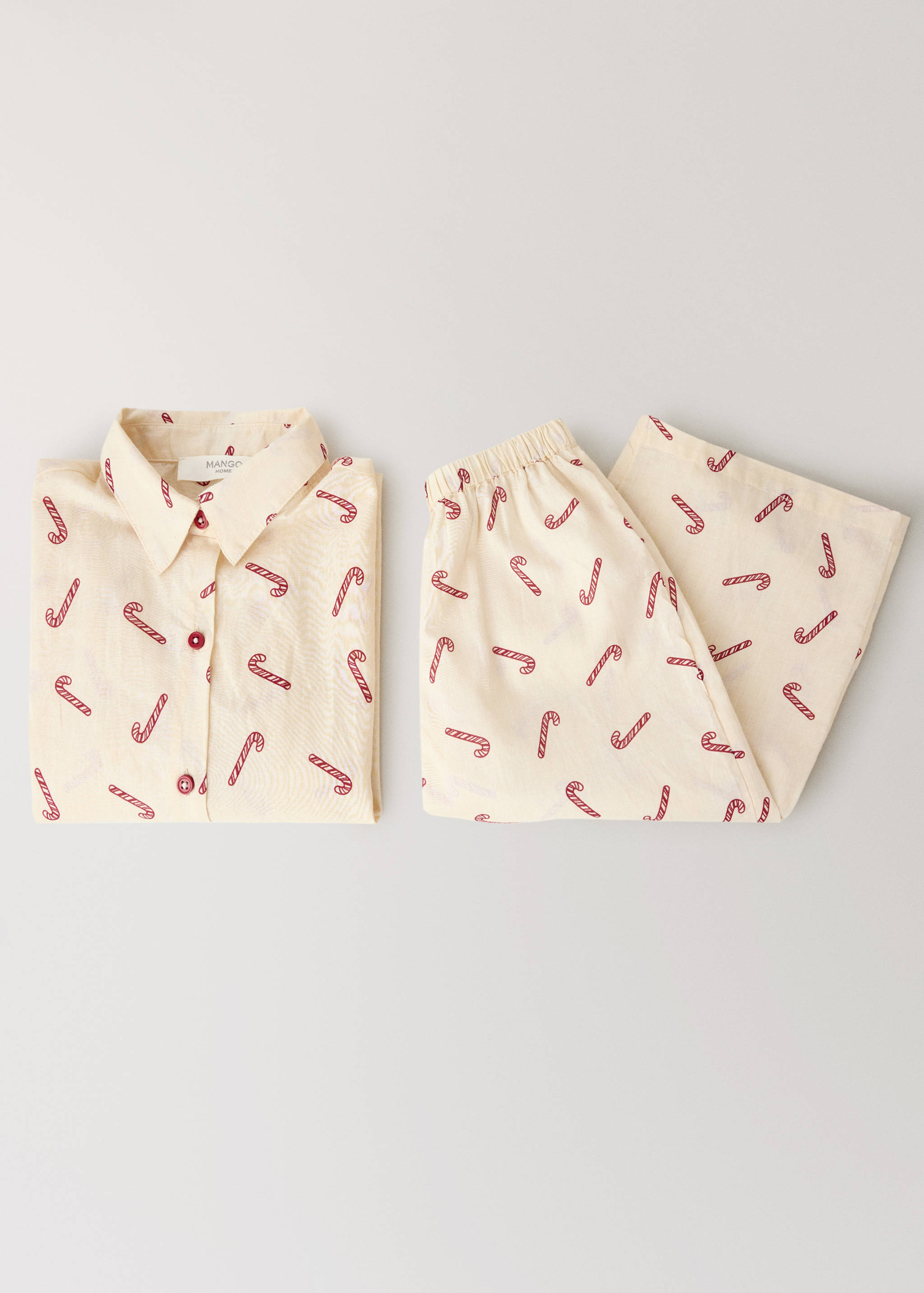 Cream and red candy cane print pajama trousers with an elasticated waistband, shown with a matching shirt.
