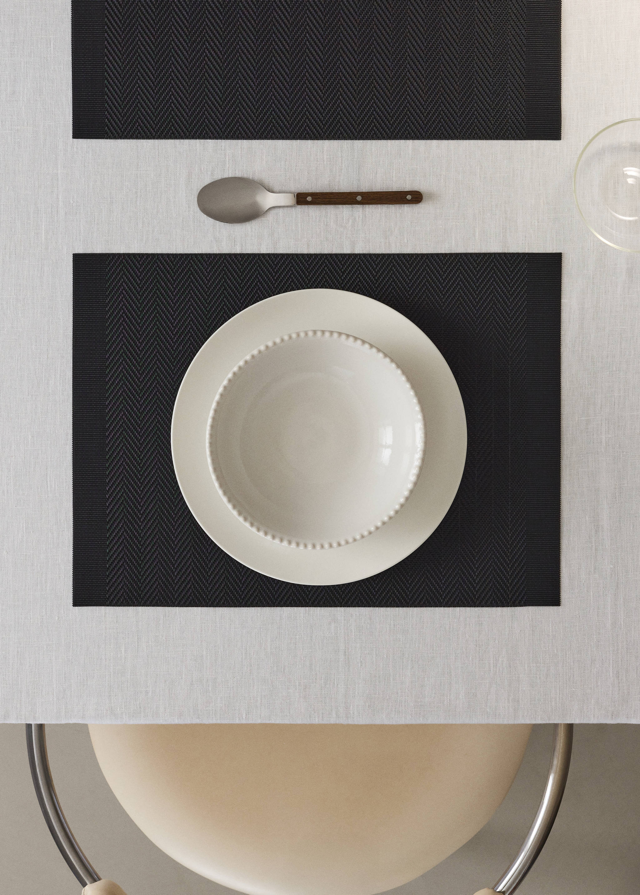 Dark grey herringbone placemats styled on a light dining table.