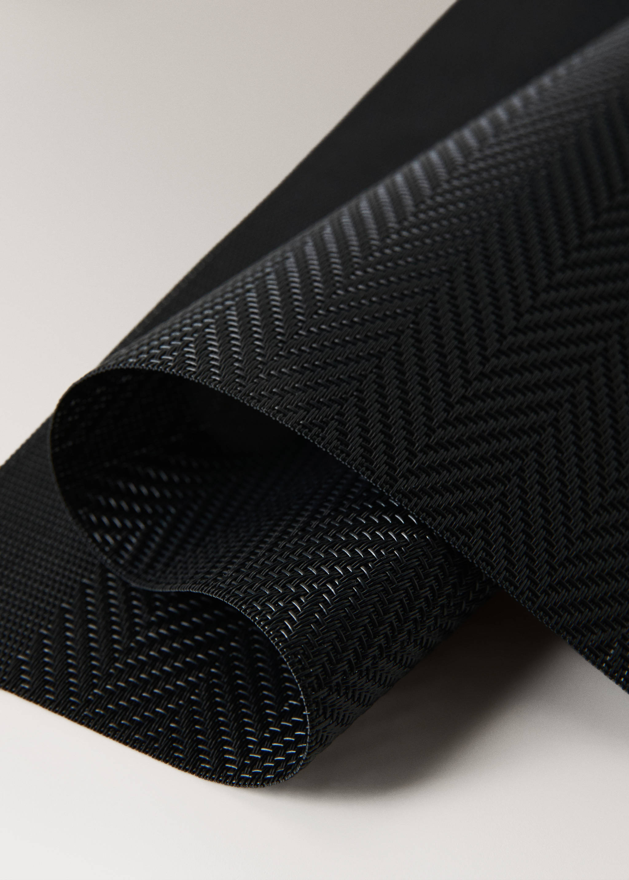 Black woven placemat with a subtle herringbone texture.