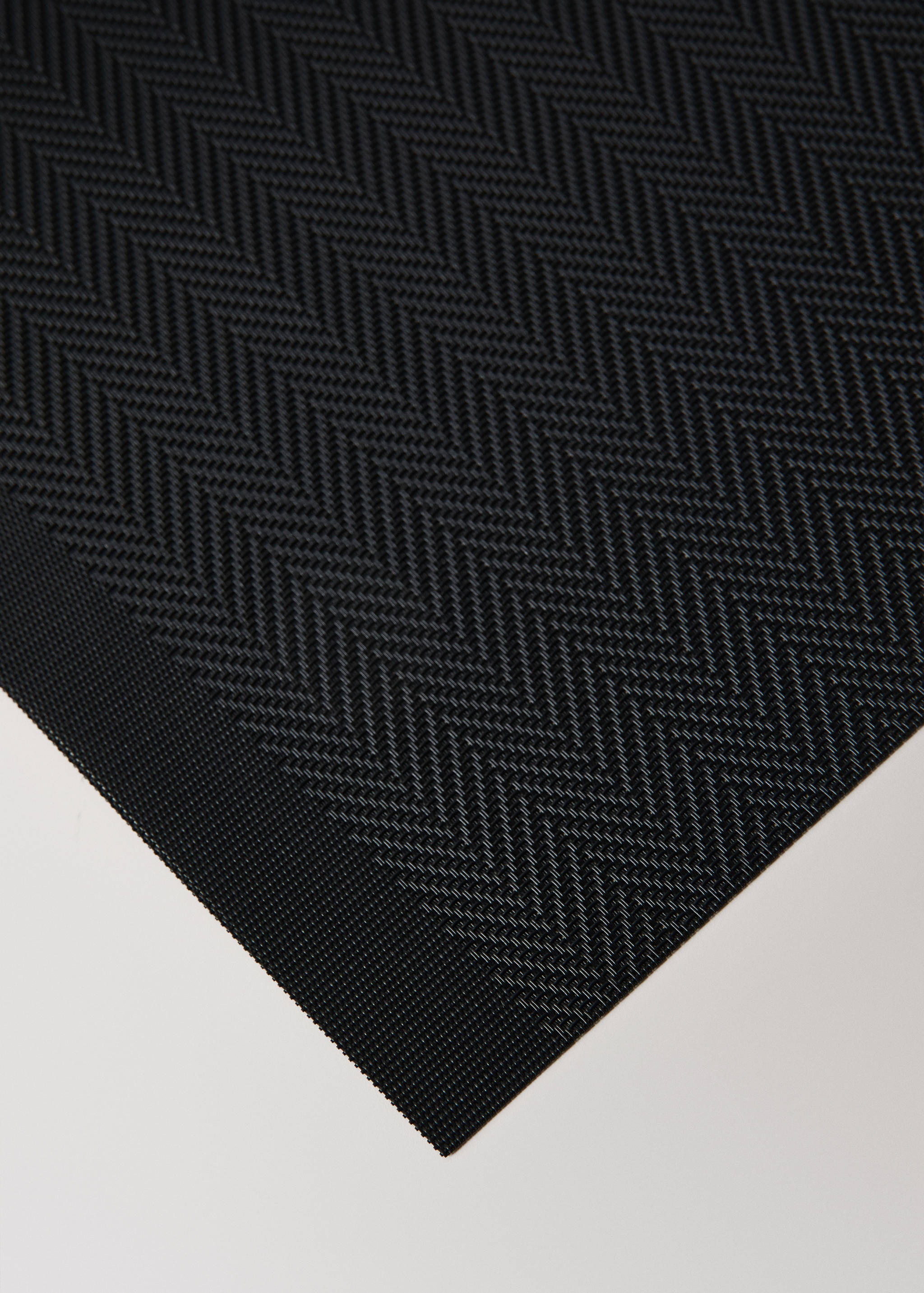 Black individual placemat with a woven herringbone pattern.