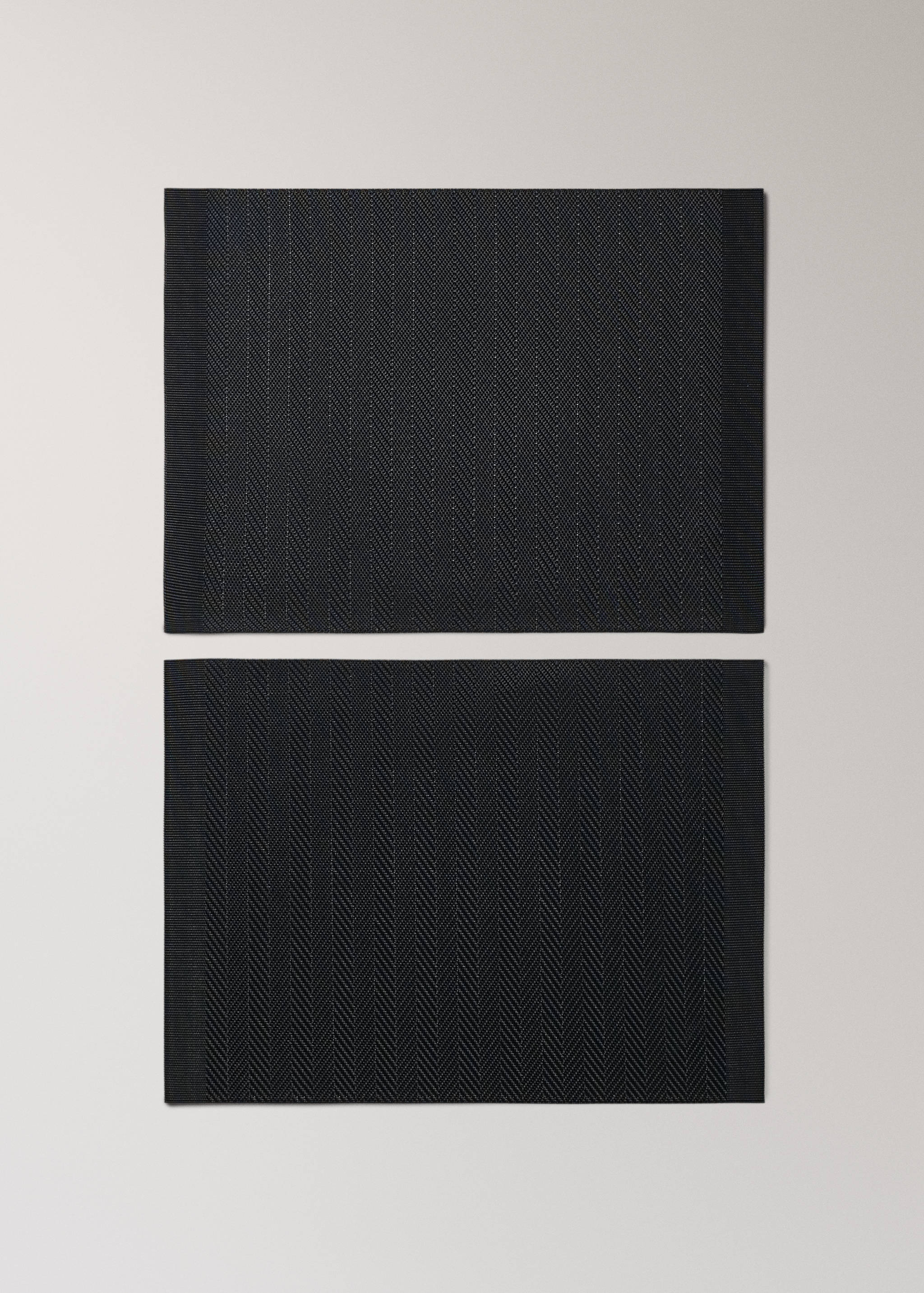 Two dark grey herringbone placemats with solid borders.