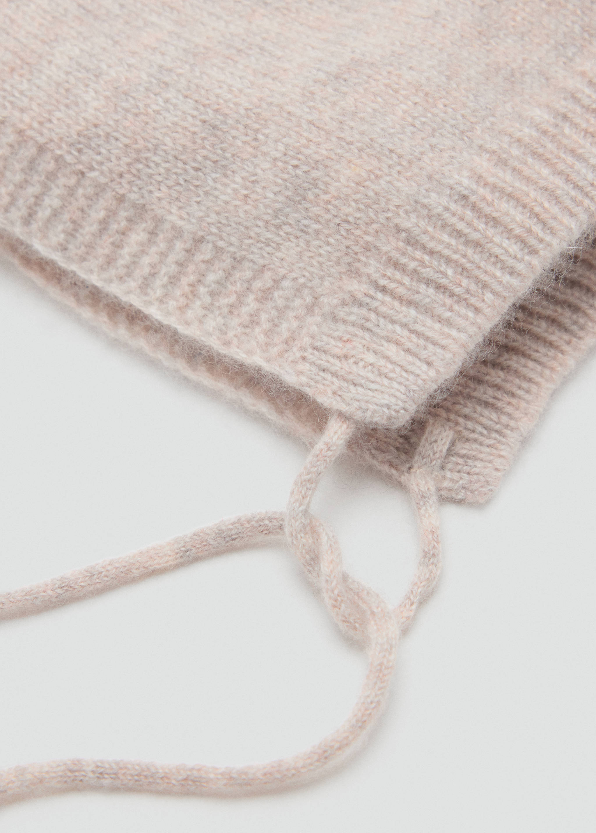 Light pink knit gorro cap with ribbed trim and ties.