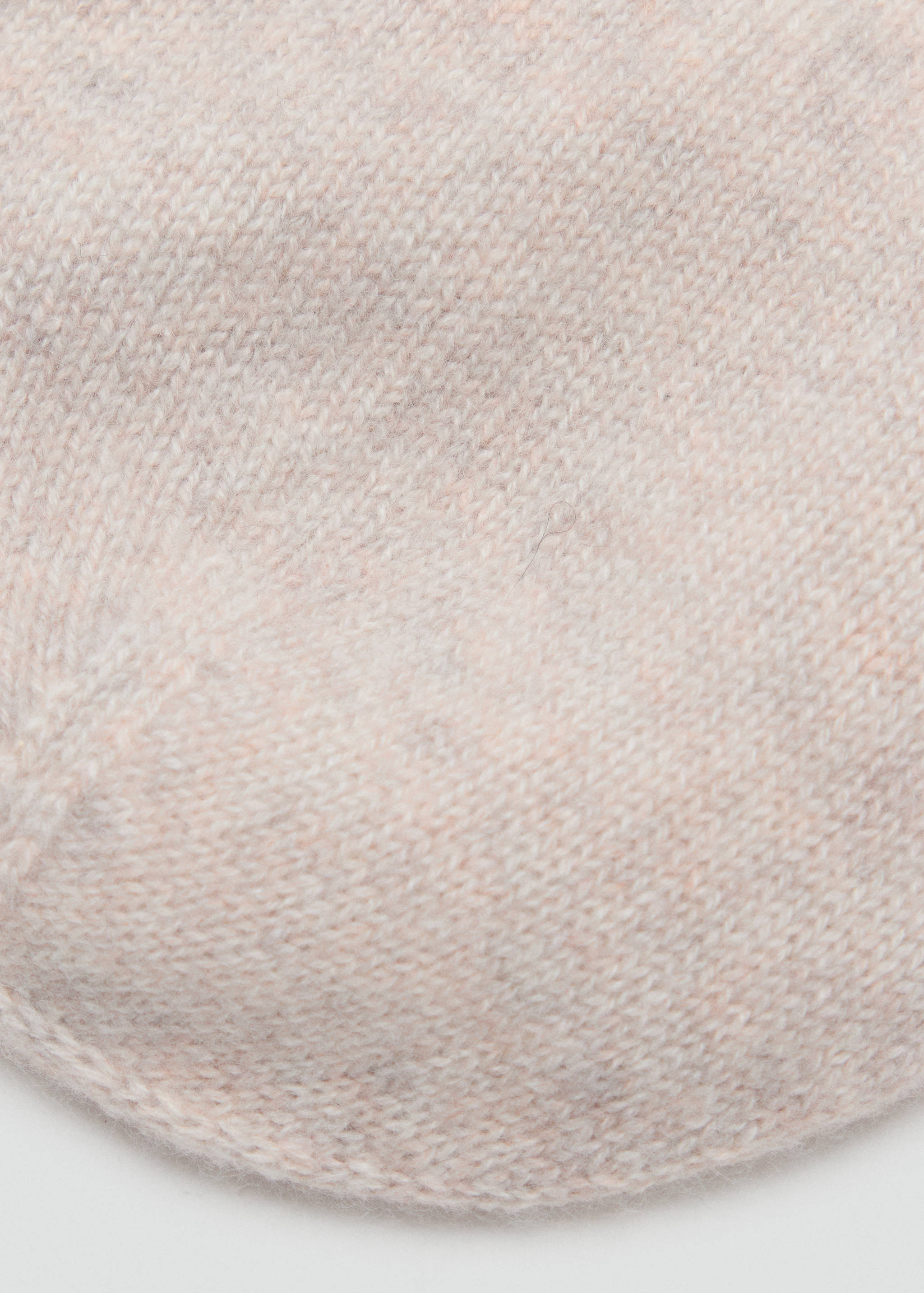 Close-up of a pink knitted beanie showing the soft yarn texture.