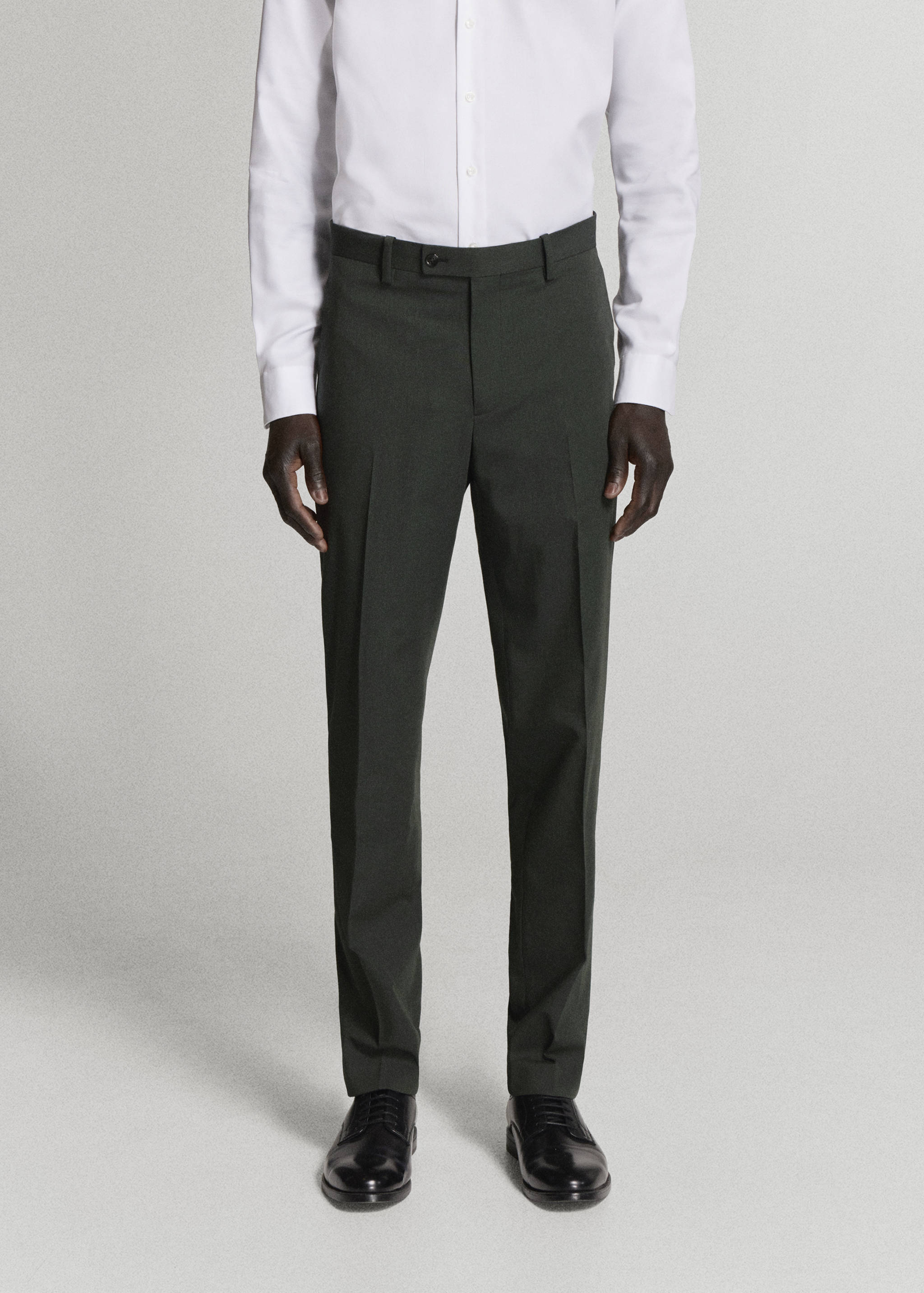 Dark green tailored trousers with belt loops and center creases, worn with a white shirt.