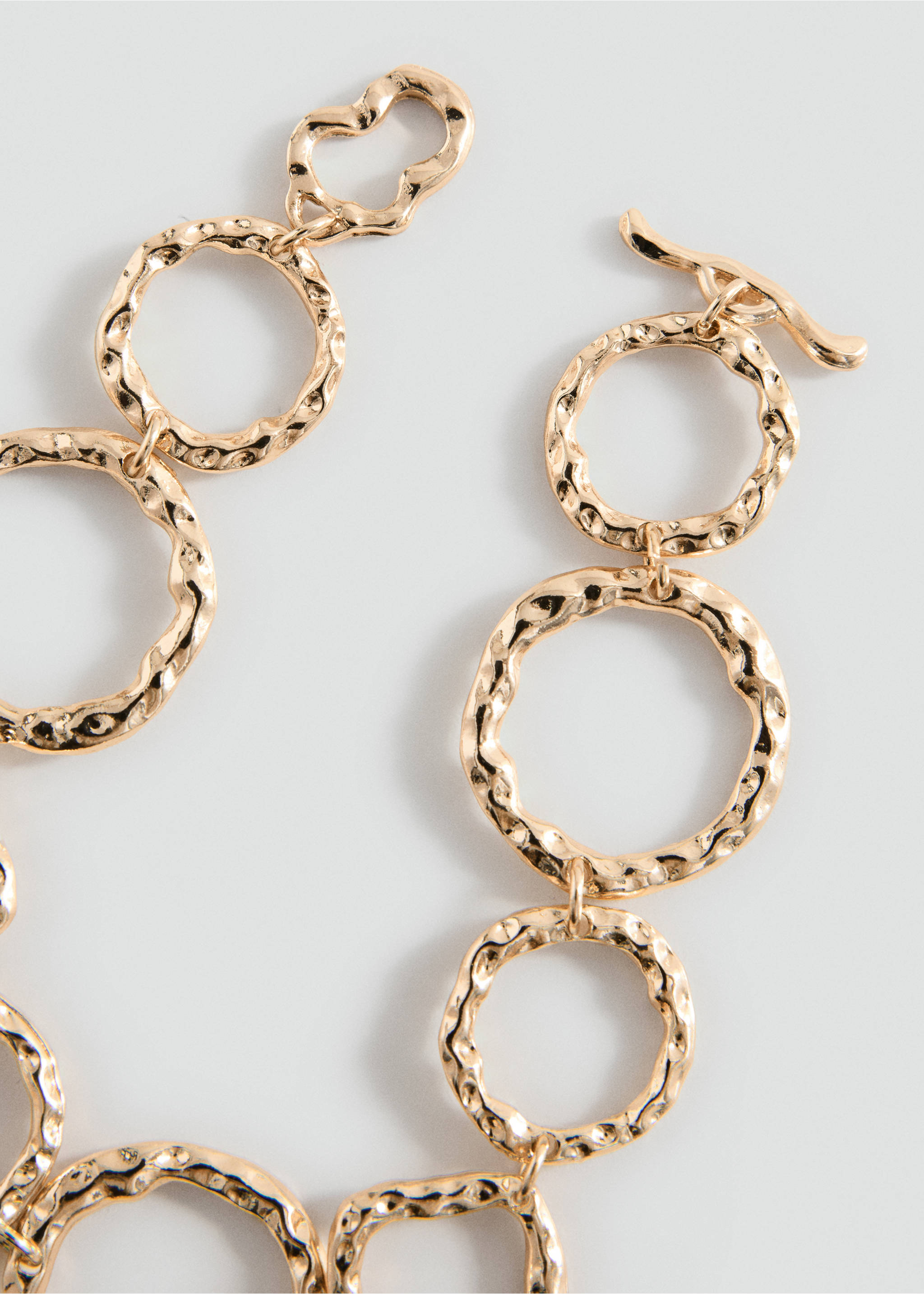 Close-up of a gold-tone hammered metal link bracelet with a T-bar clasp., Gold. Ref: 37055181-00.