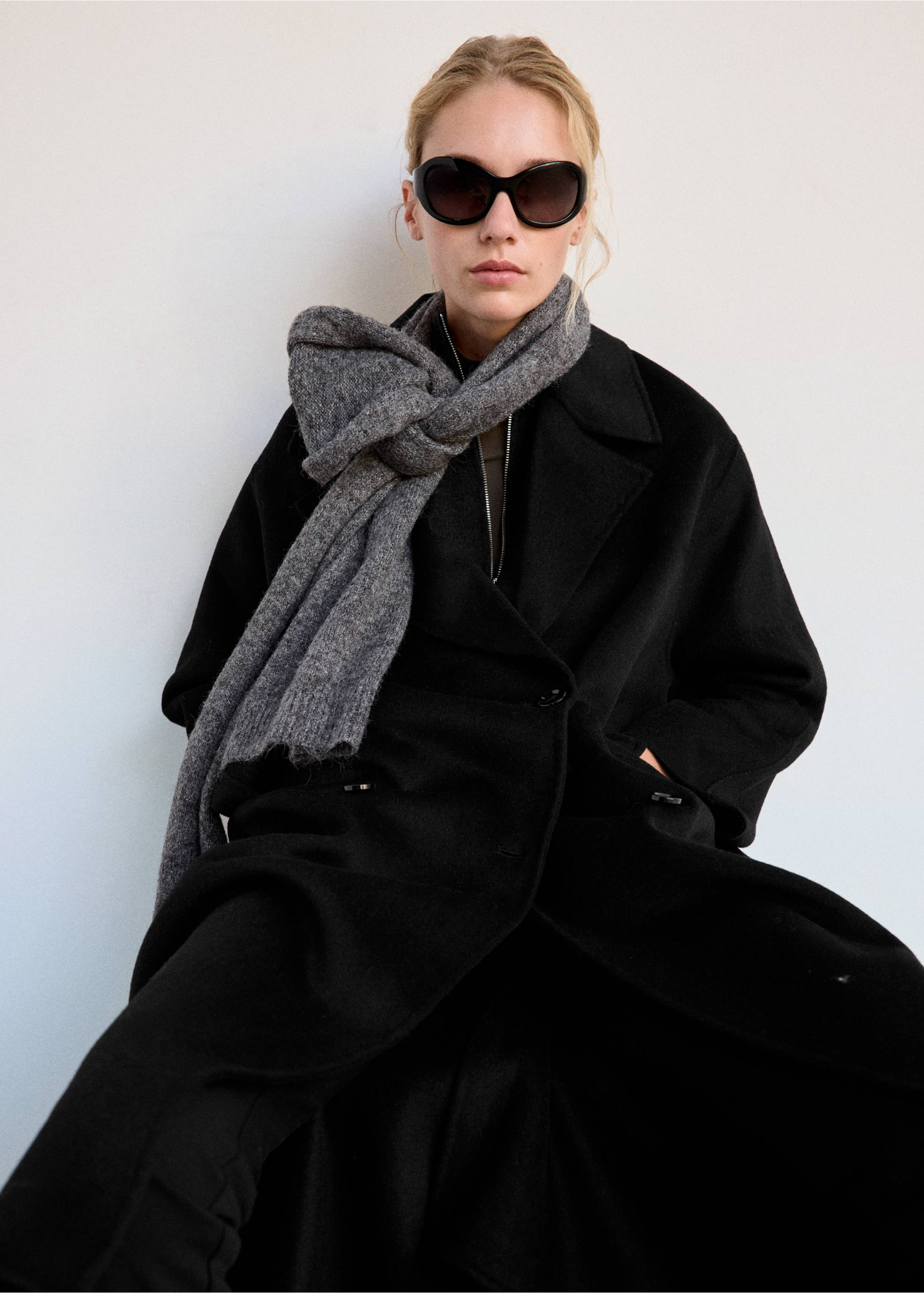 Black long coat with wide lapels and button closure, styled with a grey knitted scarf., Black. Ref: 37055845-02.