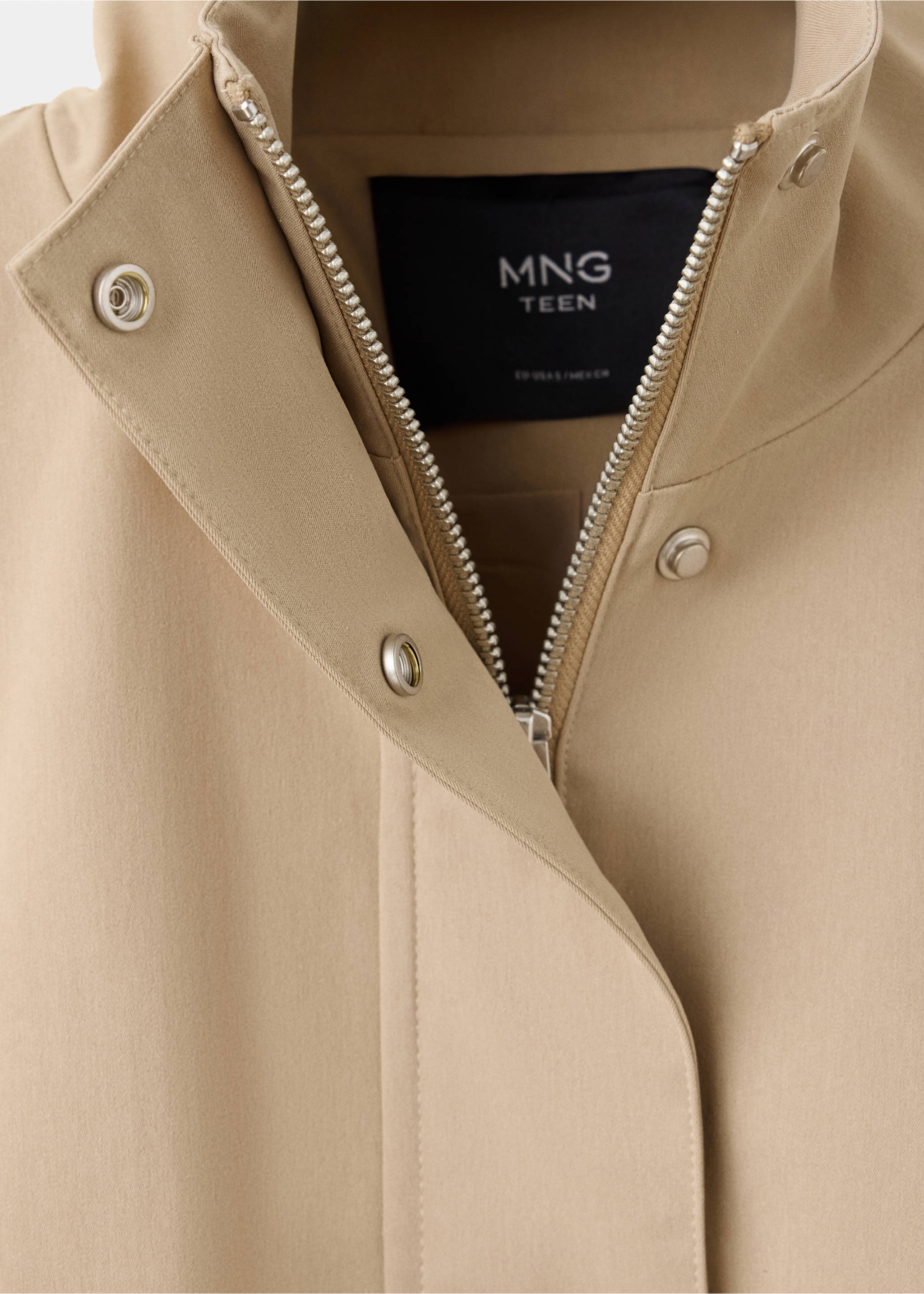 Close-up of a beige trench coat collar with a metal zip and snap button placket., Beige. Ref: 37055978-00.