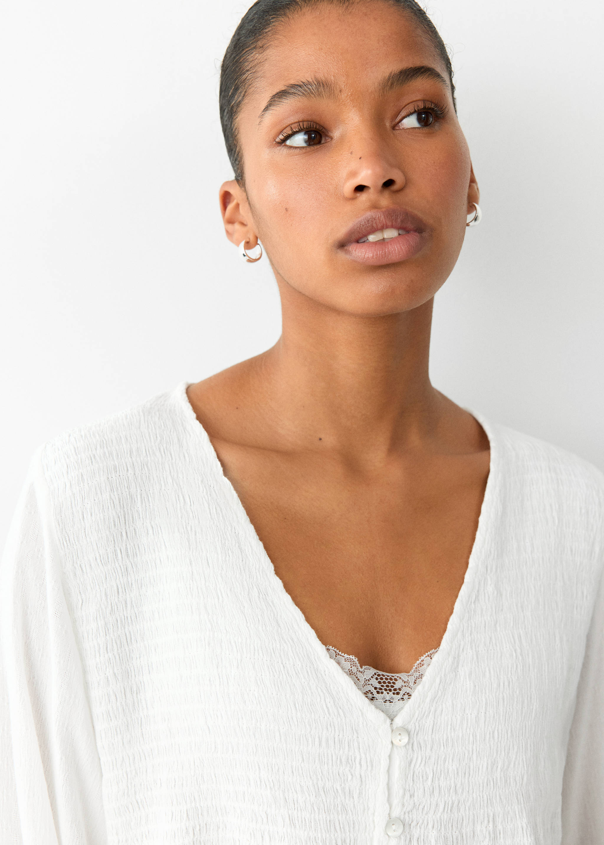 Close-up of a white textured V-neck blouse with front buttons.