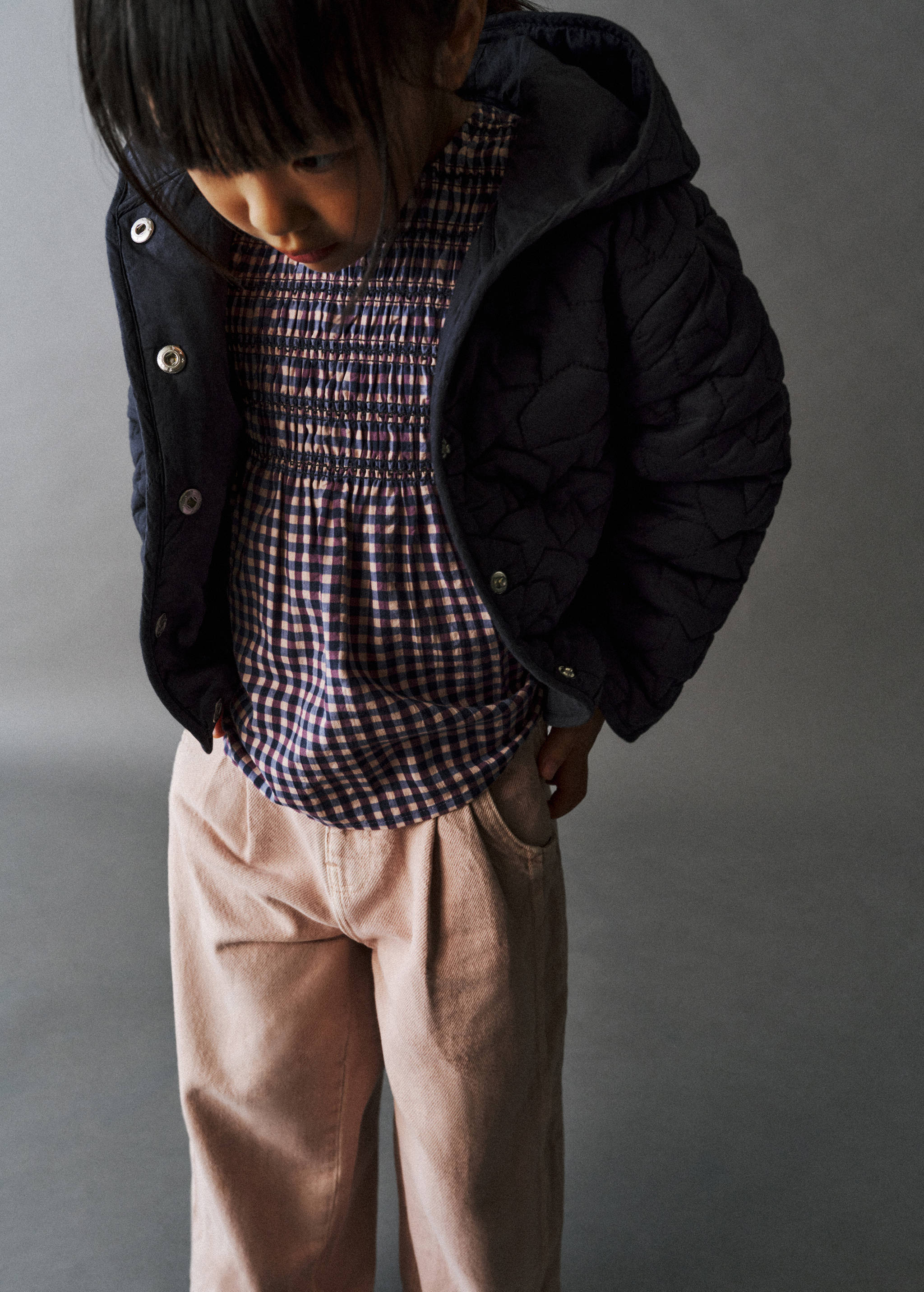 Pink jeans worn with a smocked checkered blouse and quilted jacket