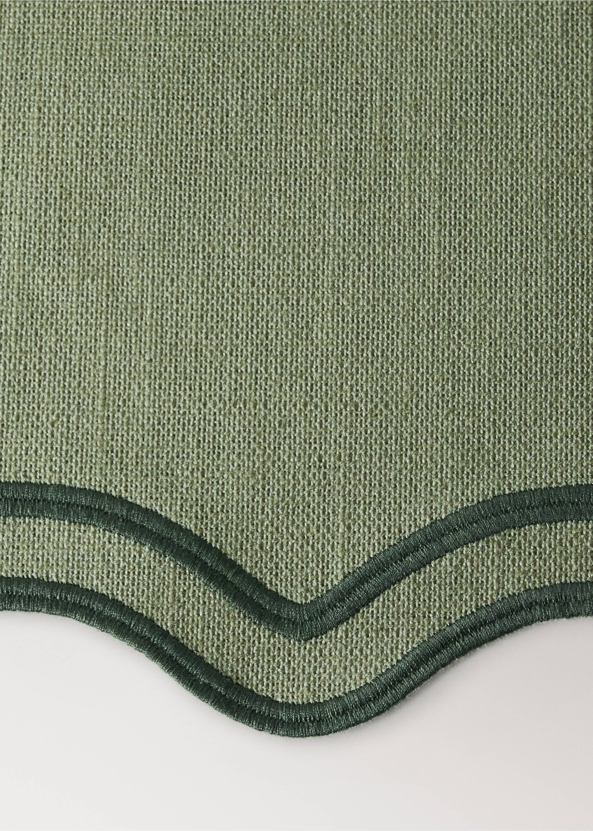 Sage green woven placemat detail with scalloped edge and dark green embroidered trim., Green. Ref: 37056332-00.