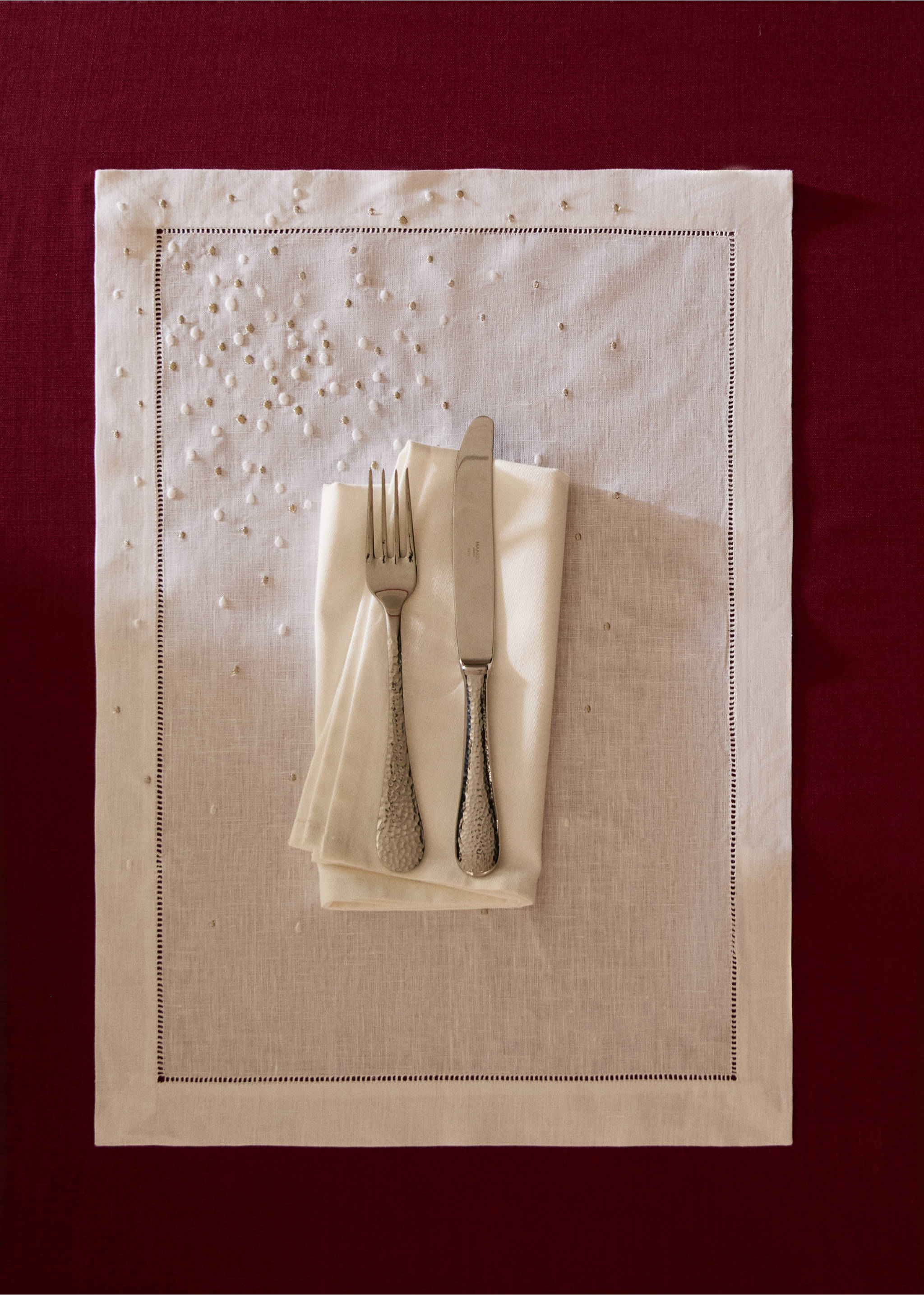 Off-white placemat with beaded embroidery and hemstitch border, styled with napkin and cutlery., White. Ref: 37056333-00.
