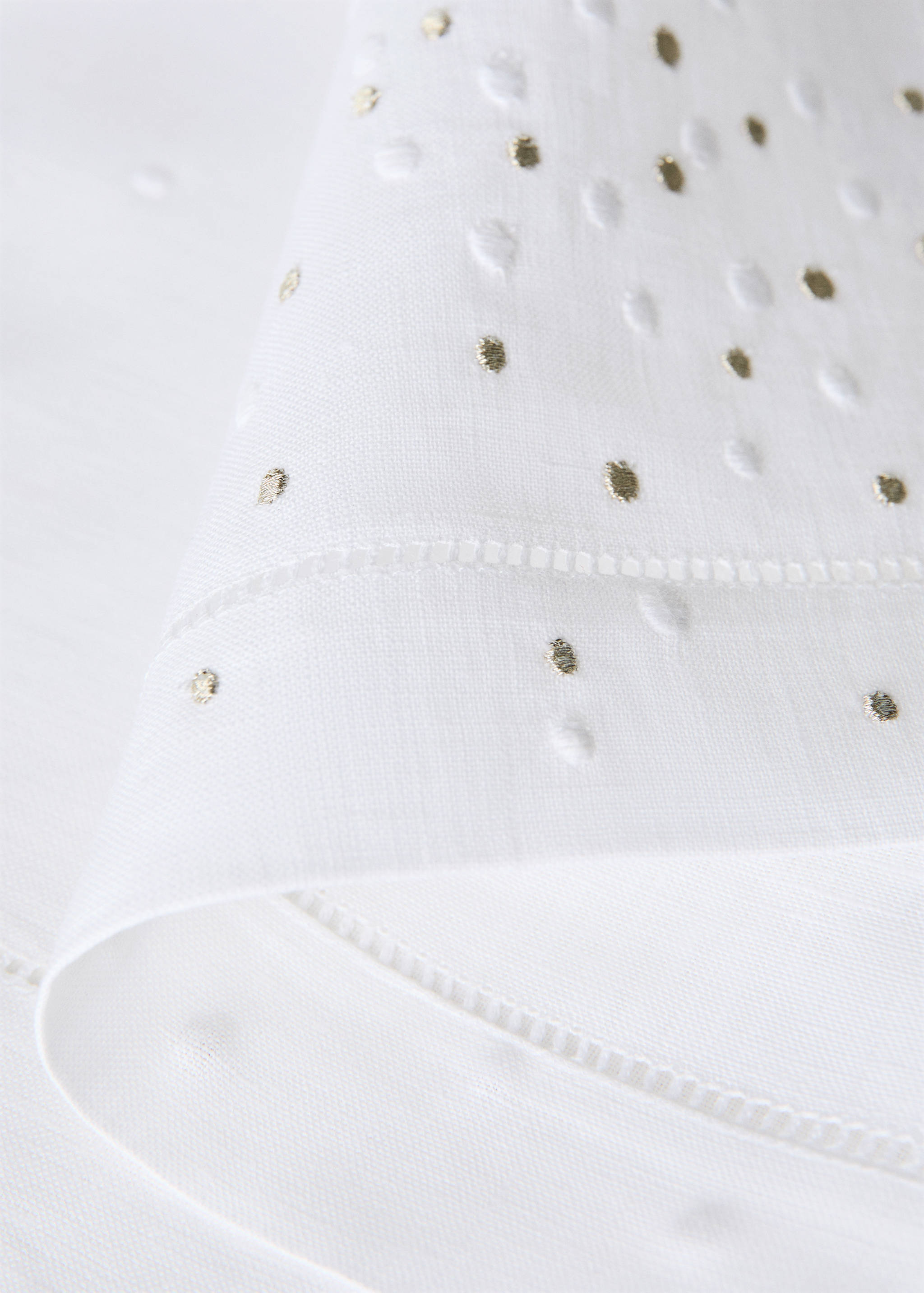 White placemat with embroidered white dots and metallic gold spots.