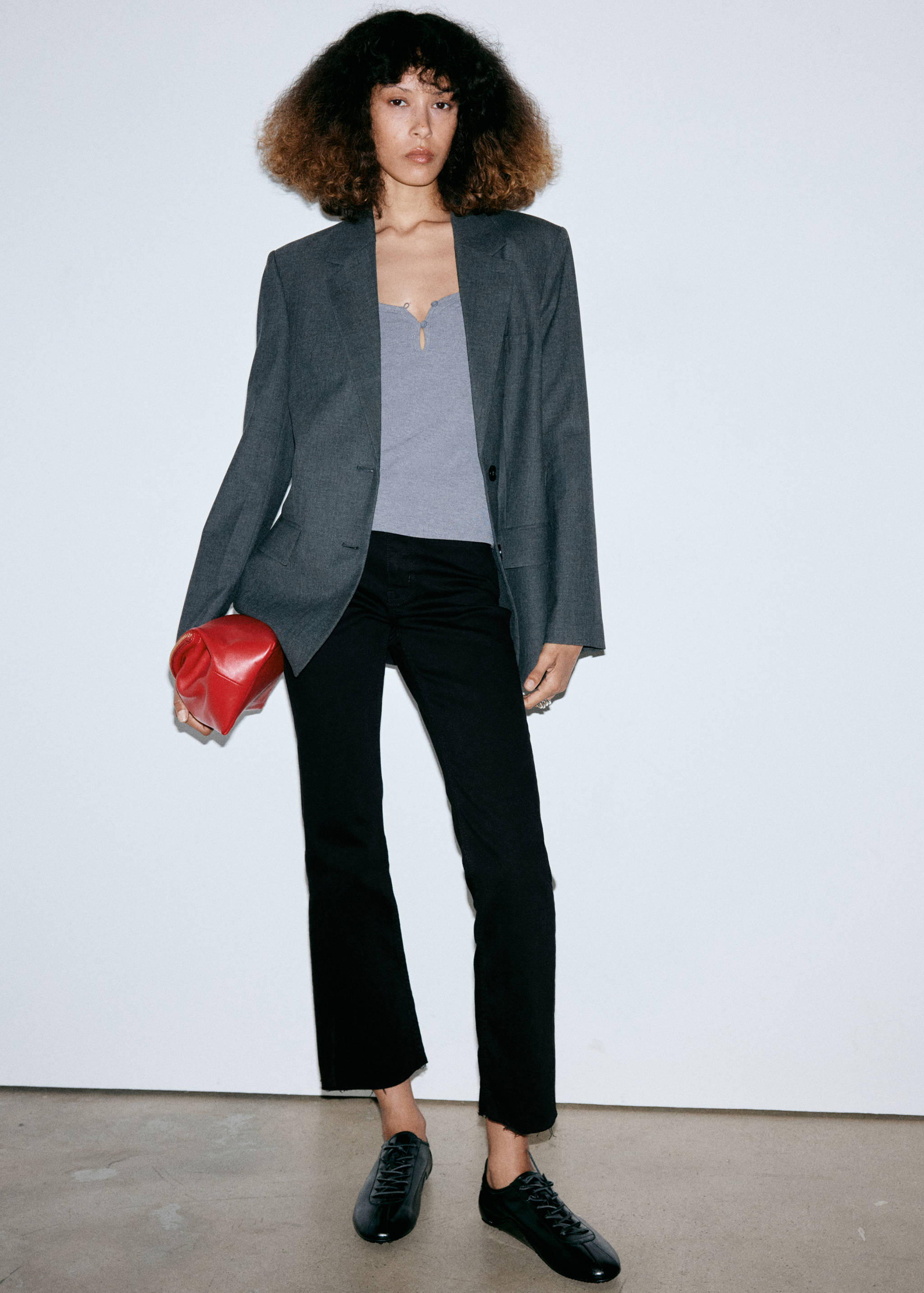 Black denim trousers with cropped raw hems, styled with a grey blazer and top.