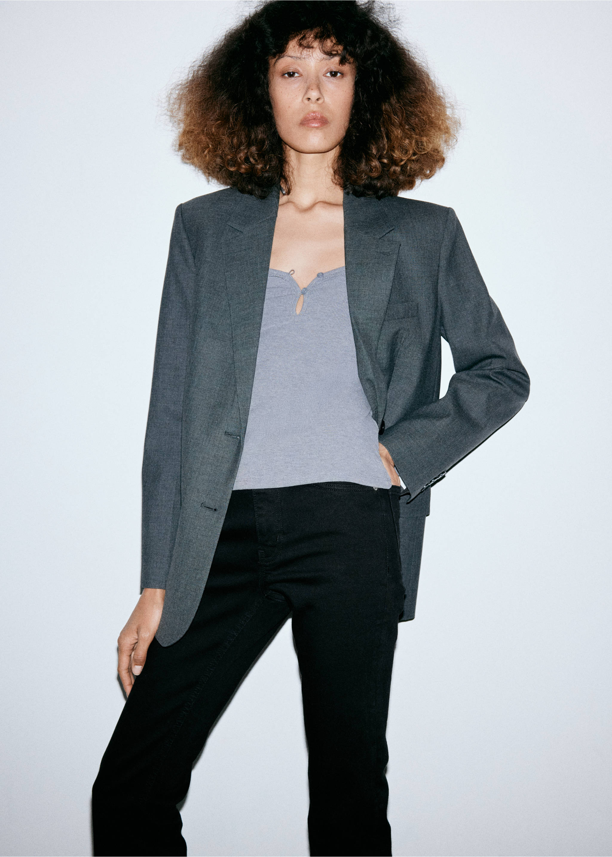 Close-up portrait of a model wearing a grey blazer, grey top, and black denim trousers., Black denim. Ref: 37056368-00.